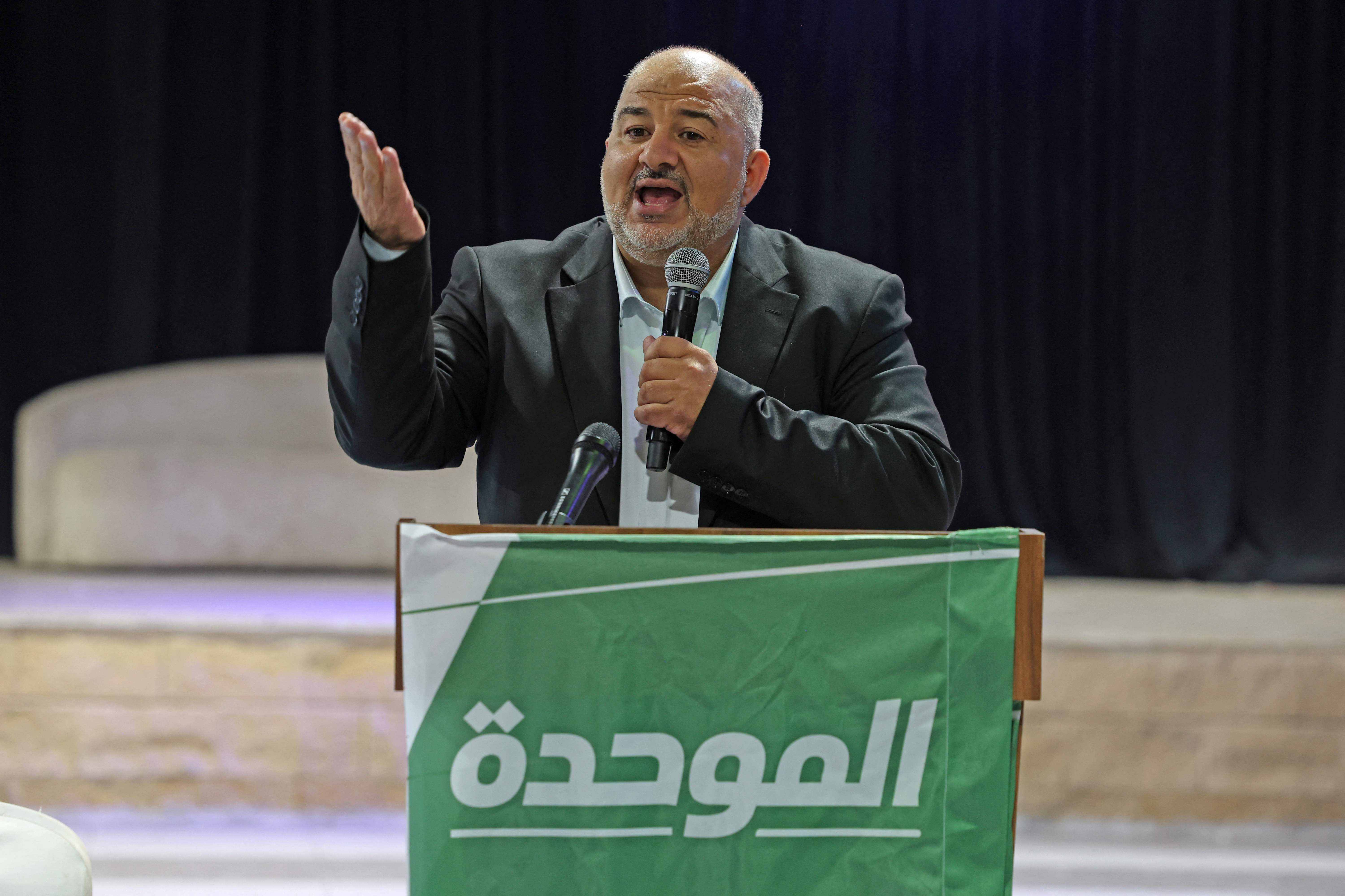 Ein Mann spricht bei einer Kundgebung am Rednerpult mit grünem Banner und arabischer Aufschrift.