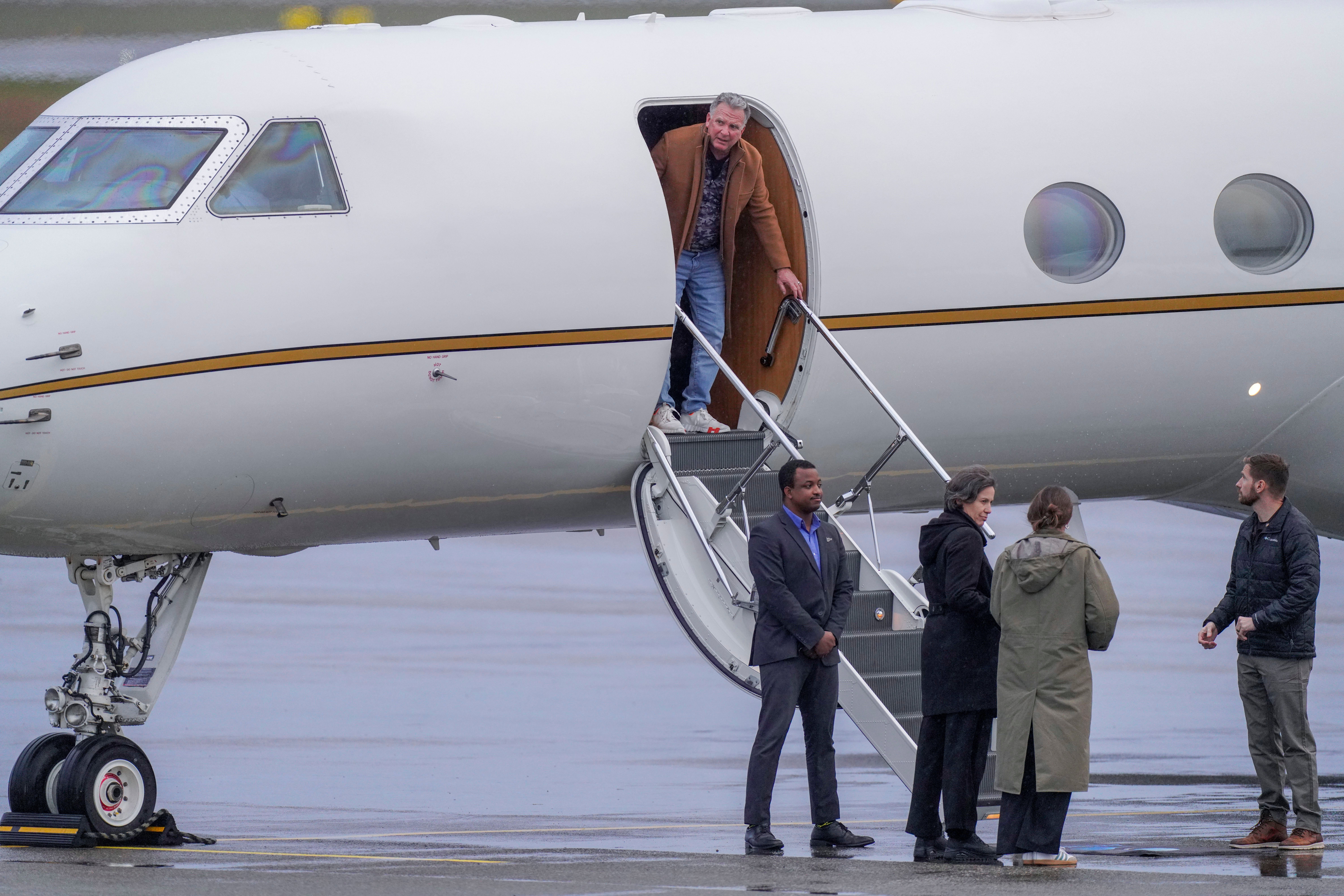 Ein Mann steigt aus einem Privatflugzeug, mehrere Personen warten unten auf dem Rollfeld.