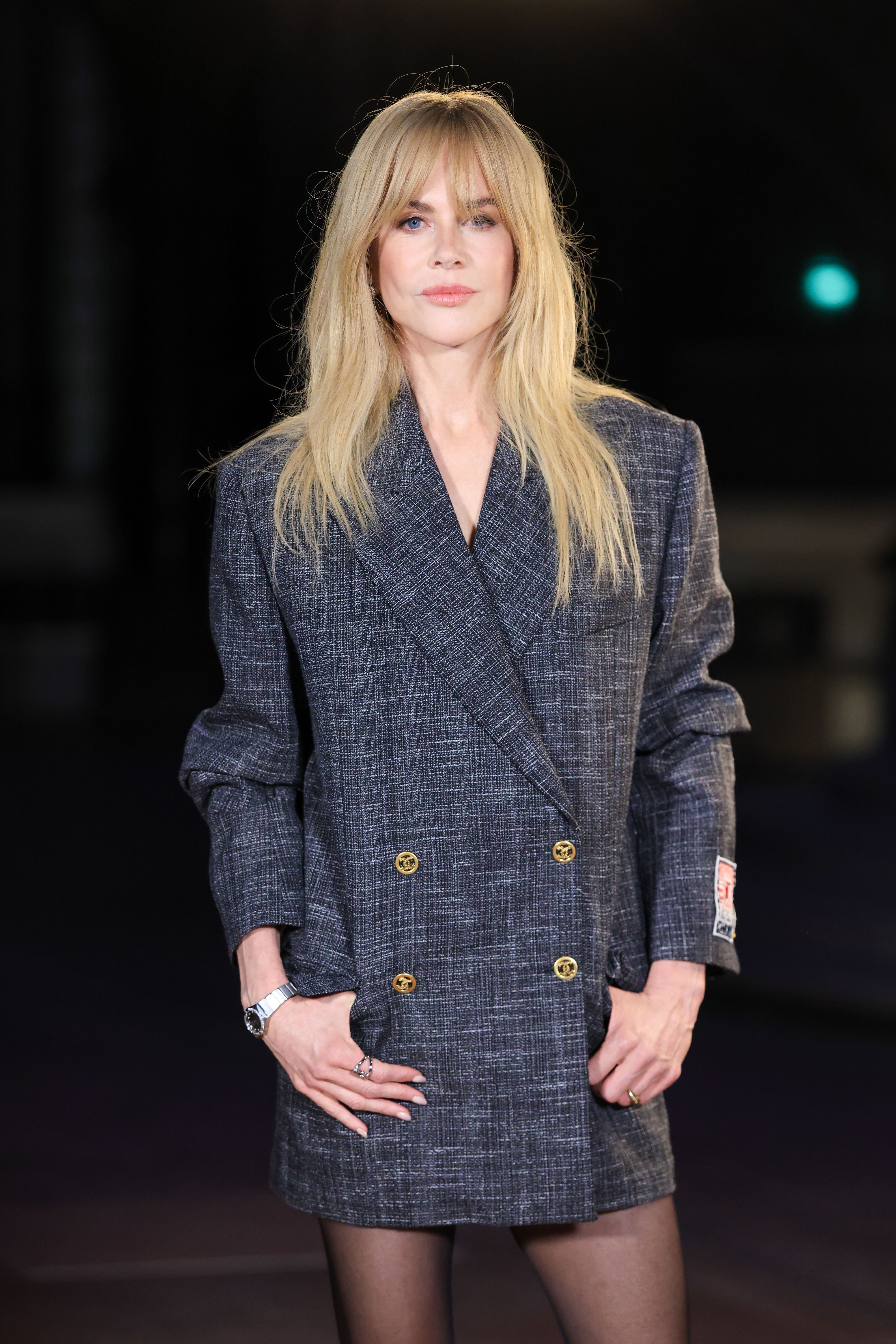 Eine Frau mit langen blonden Haaren trägt ein graues, kariertes Blazer-Kleid.