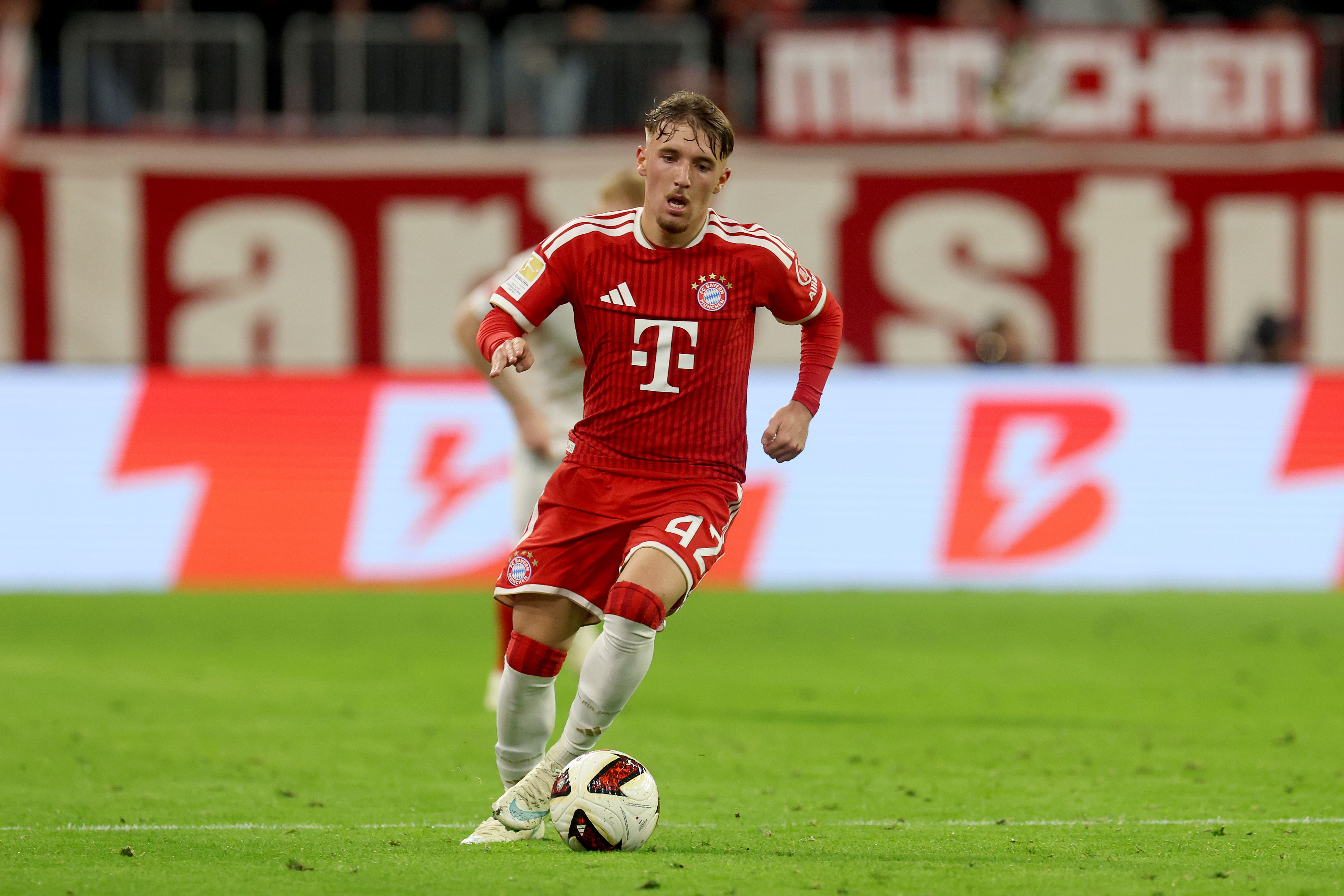 Ein FC Bayern-Spieler im roten Trikot läuft mit dem Ball über das Spielfeld in der Allianz Arena.