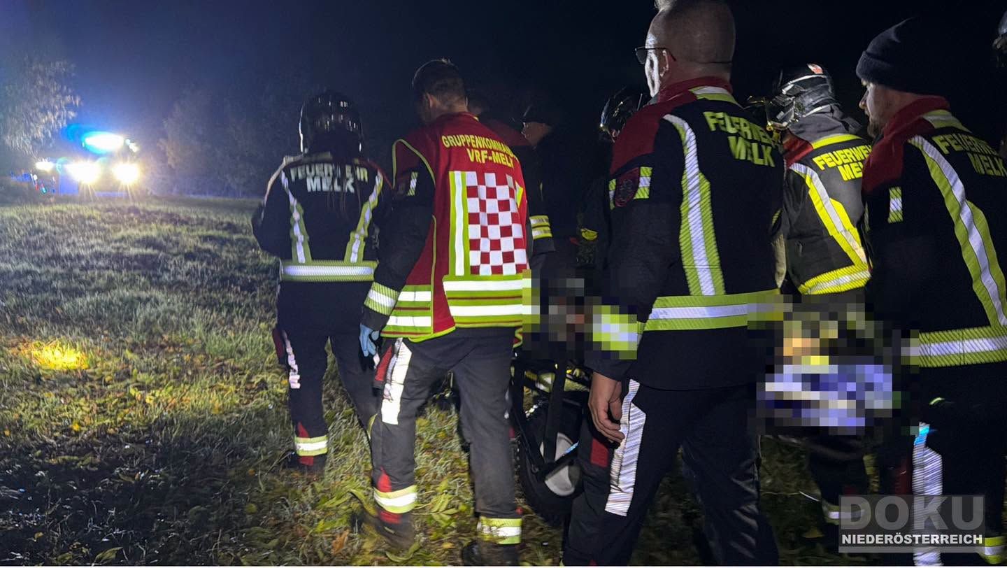 Feuerwehrleute retten bei Nacht eine Person, die auf einer Trage transportiert wird.