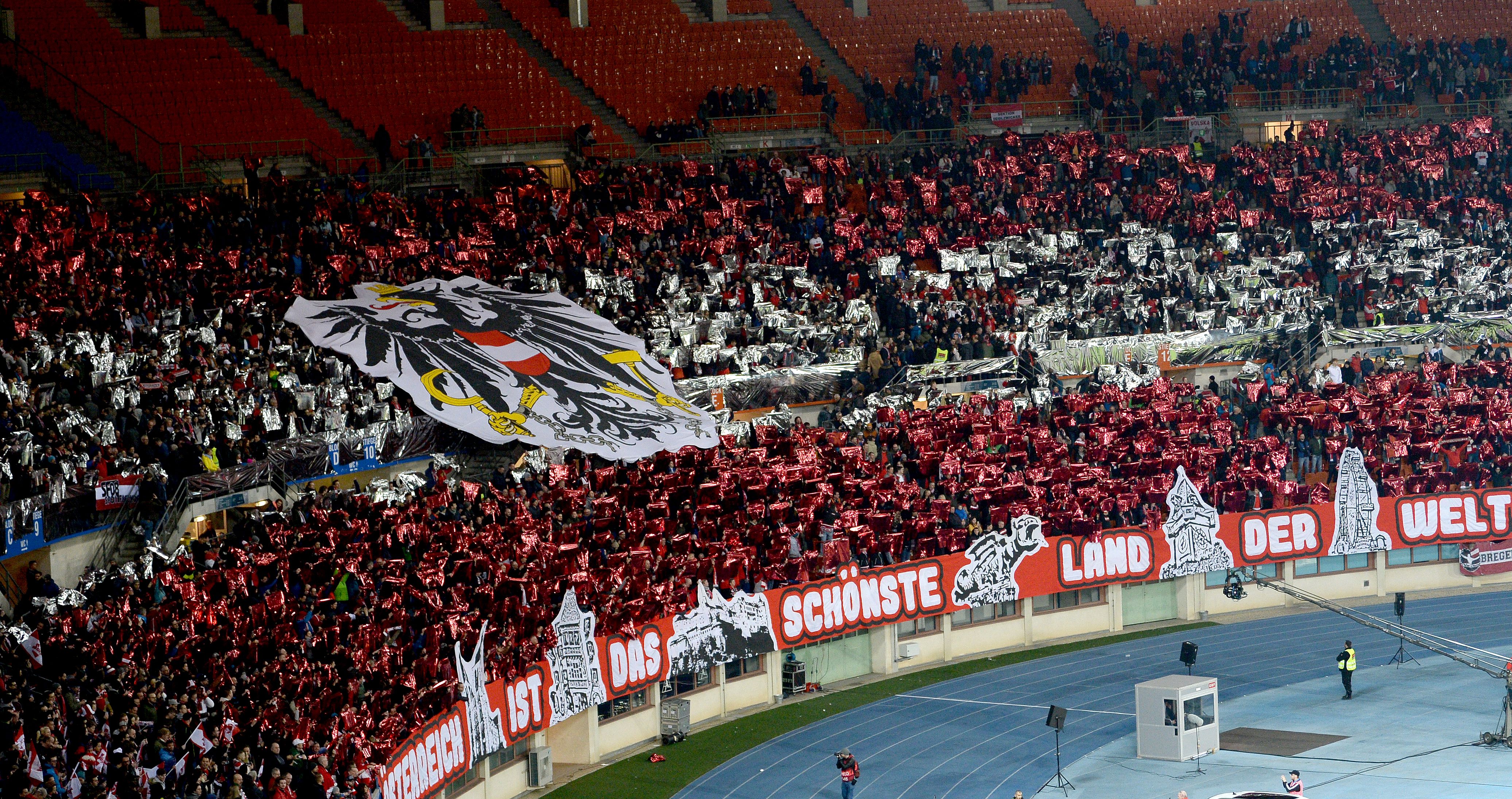 Österreichische Fans mit rotem Glanzpapier und großer Adler-Fahne im Ernst Happel-Stadion, Wien.