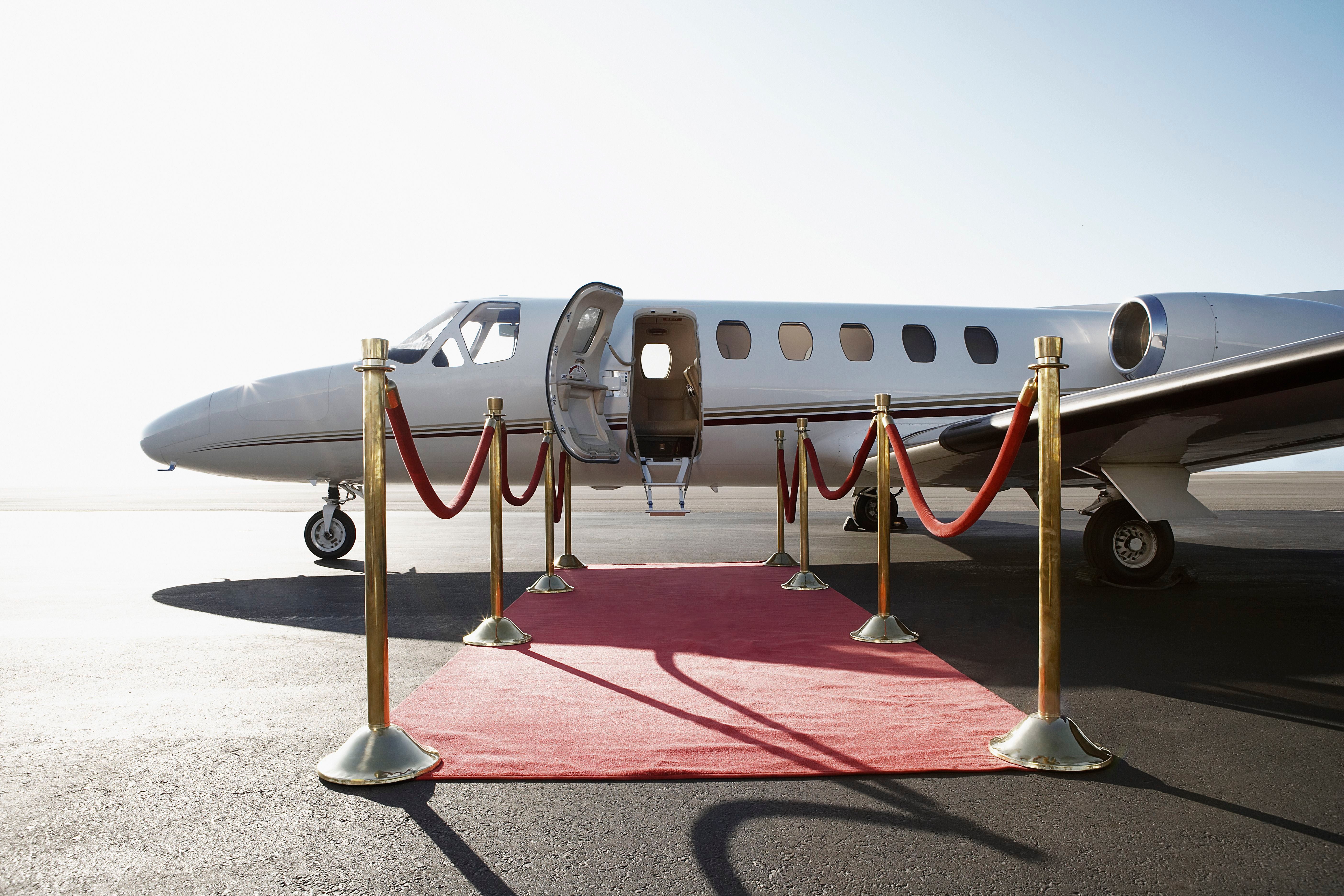 Privatjet mit rotem Teppich und Absperrungen am Flugfeld bei geöffneter Tür.