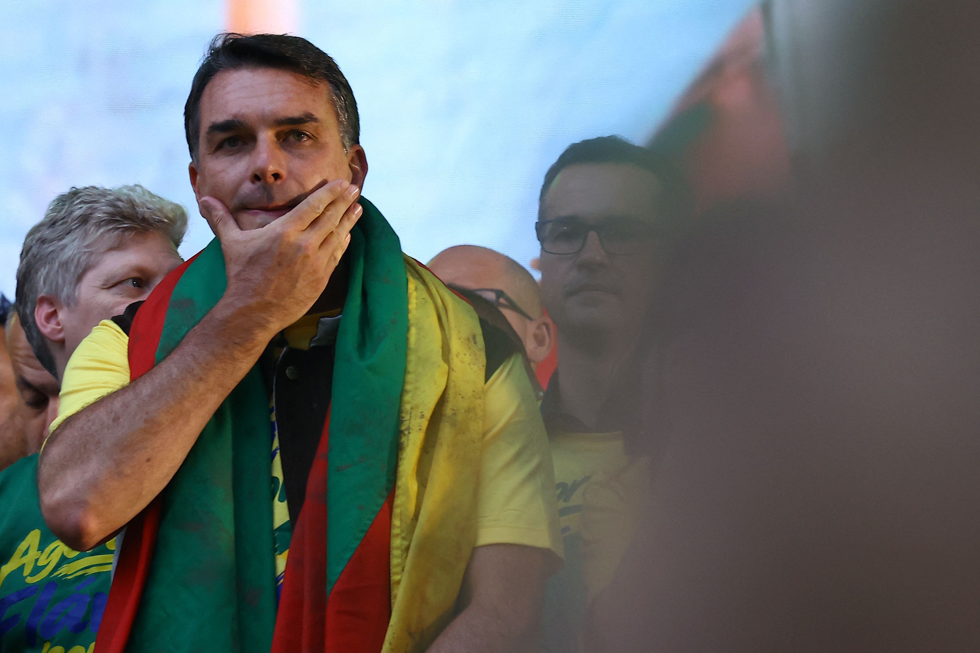 Ein Mann im gelben T-Shirt mit einer Flagge über der Schulter steht nachdenklich auf einer Bühne.