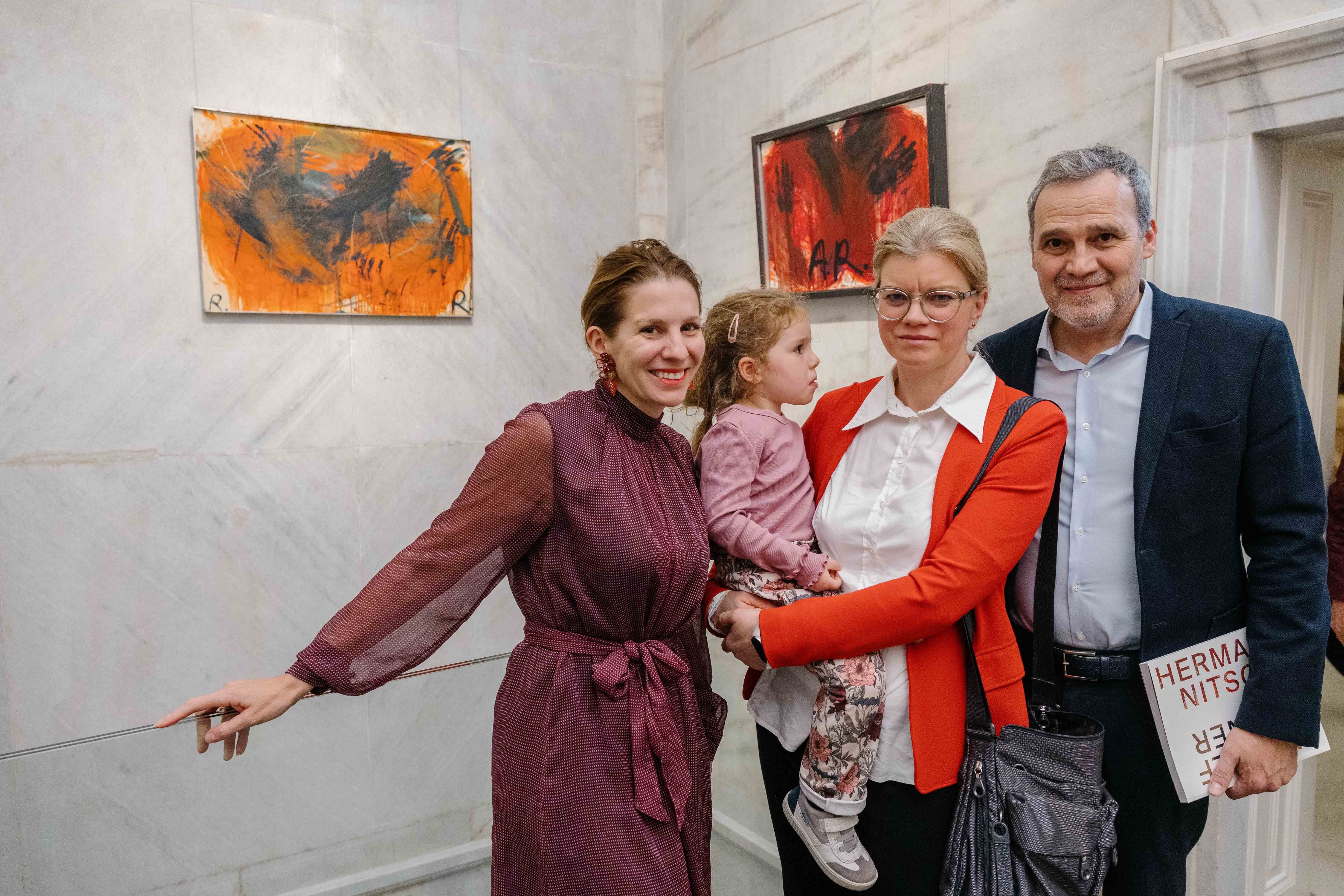 Vier Personen, darunter ein kleines Kind, posieren in einer Galerie vor abstrakter Kunst.