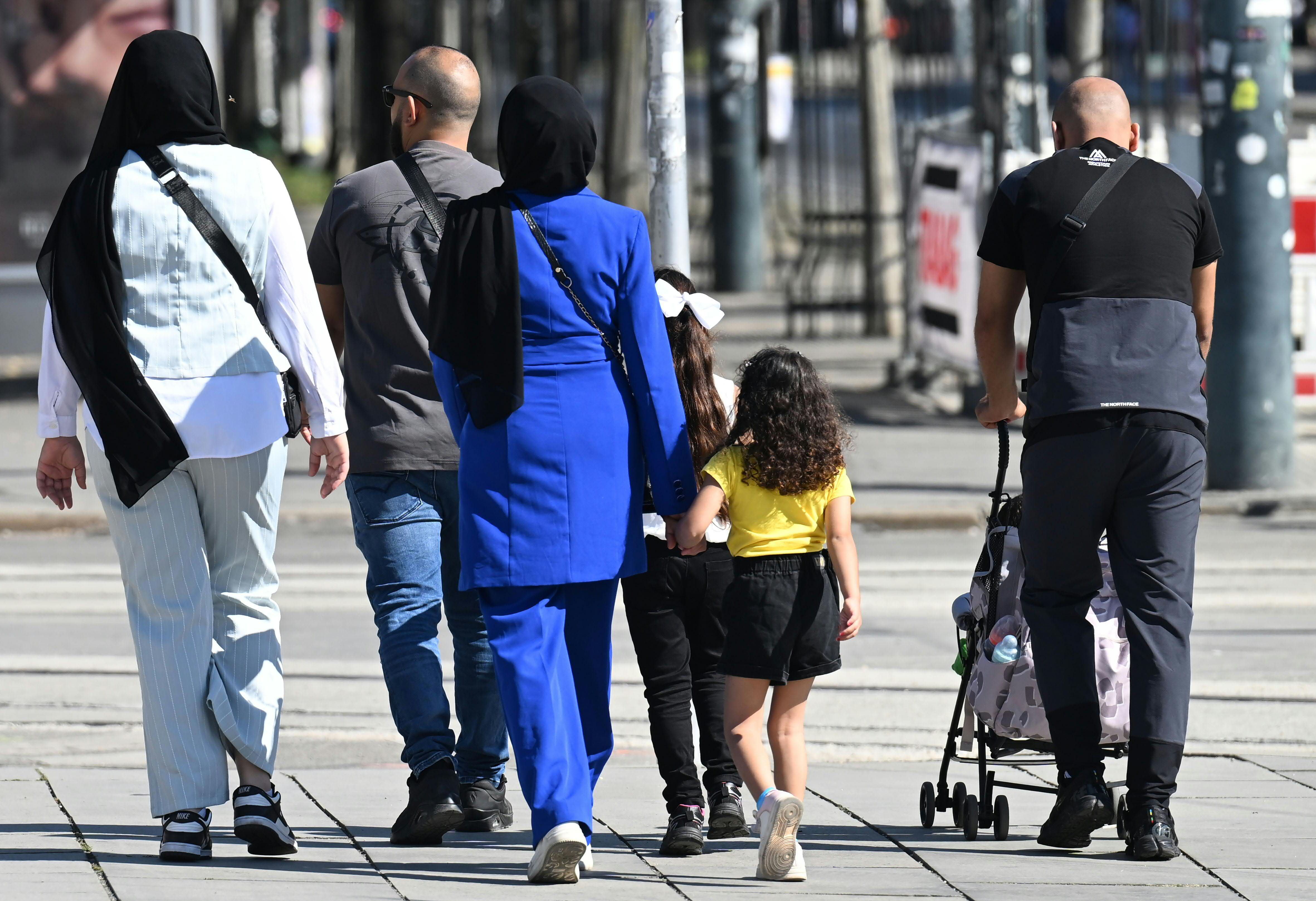Eine Gruppe von Erwachsenen und Kindern geht gemeinsam auf einem Gehweg in Wien spazieren.
