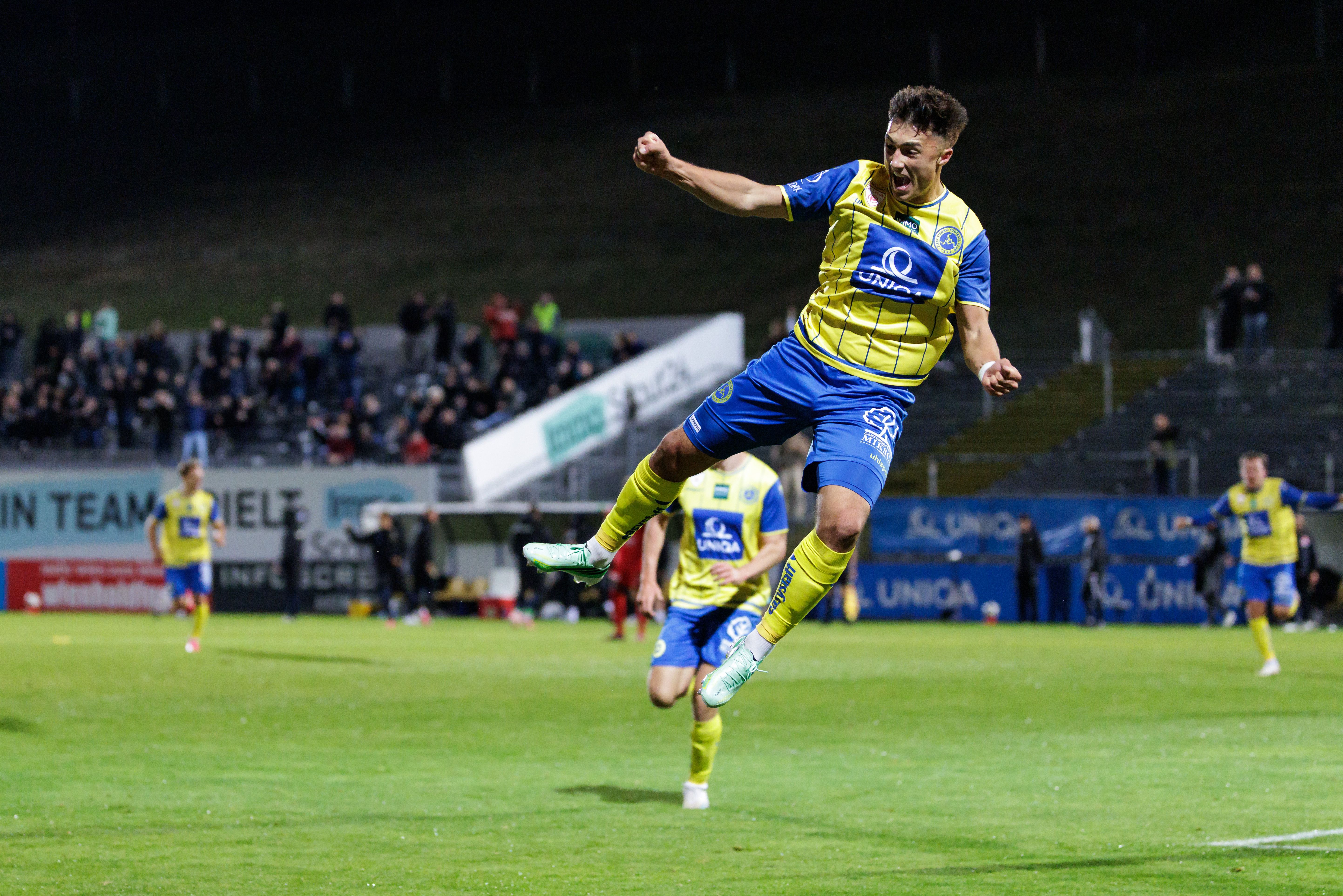 Vienna-Stürmer Bernhard Zimmermann springt im gelb-blauen Trikot mit geballten Fäusten jubelnd in die Luft.