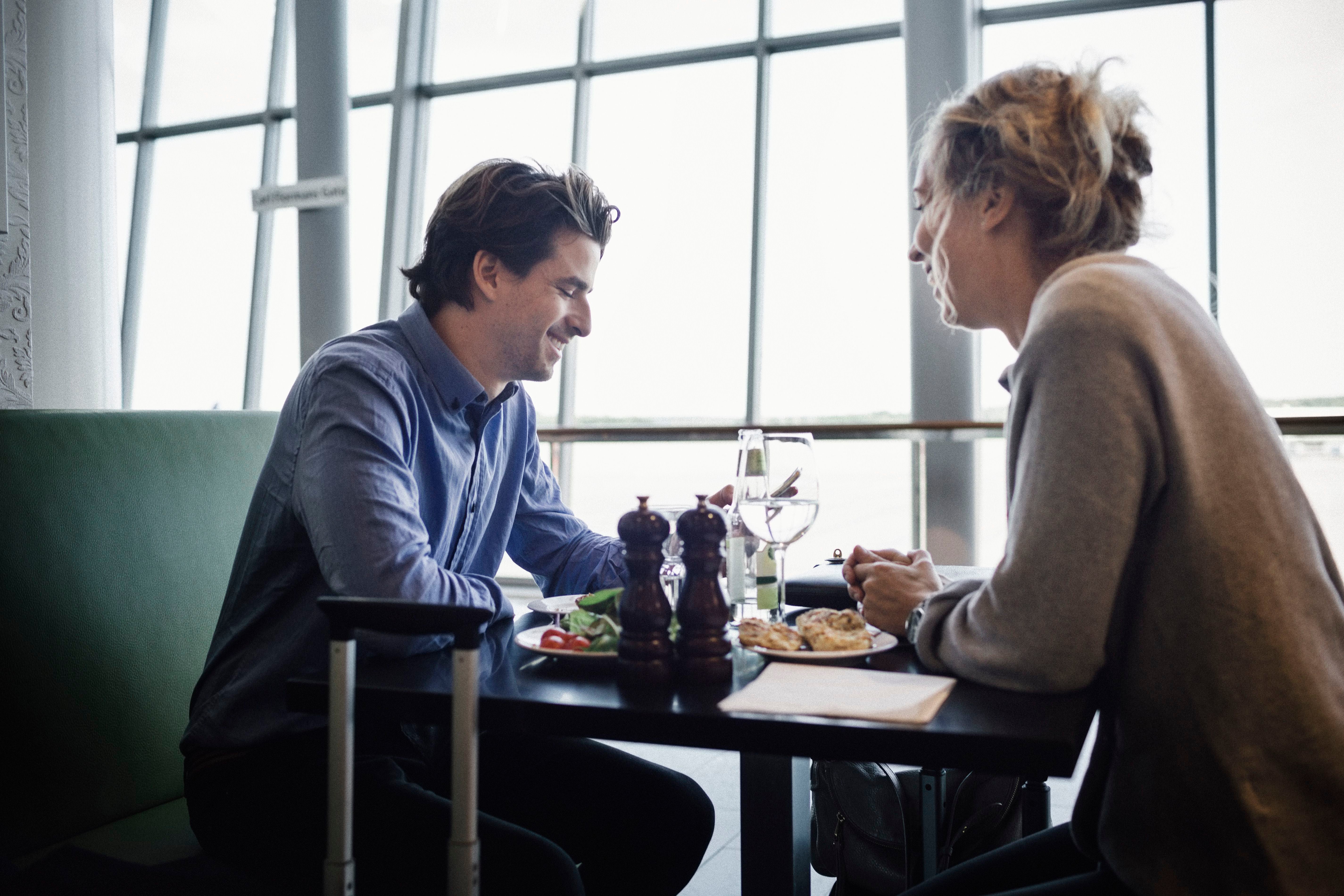 Ein Mann und eine Frau sitzen in einem Restaurant am Tisch und unterhalten sich beim Essen.