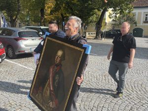 Direktor Josef Glanz trägt voller Freude, begleitet von den beiden Kriminalbeamten, das Gemälde zurück zum Klostergasthof.