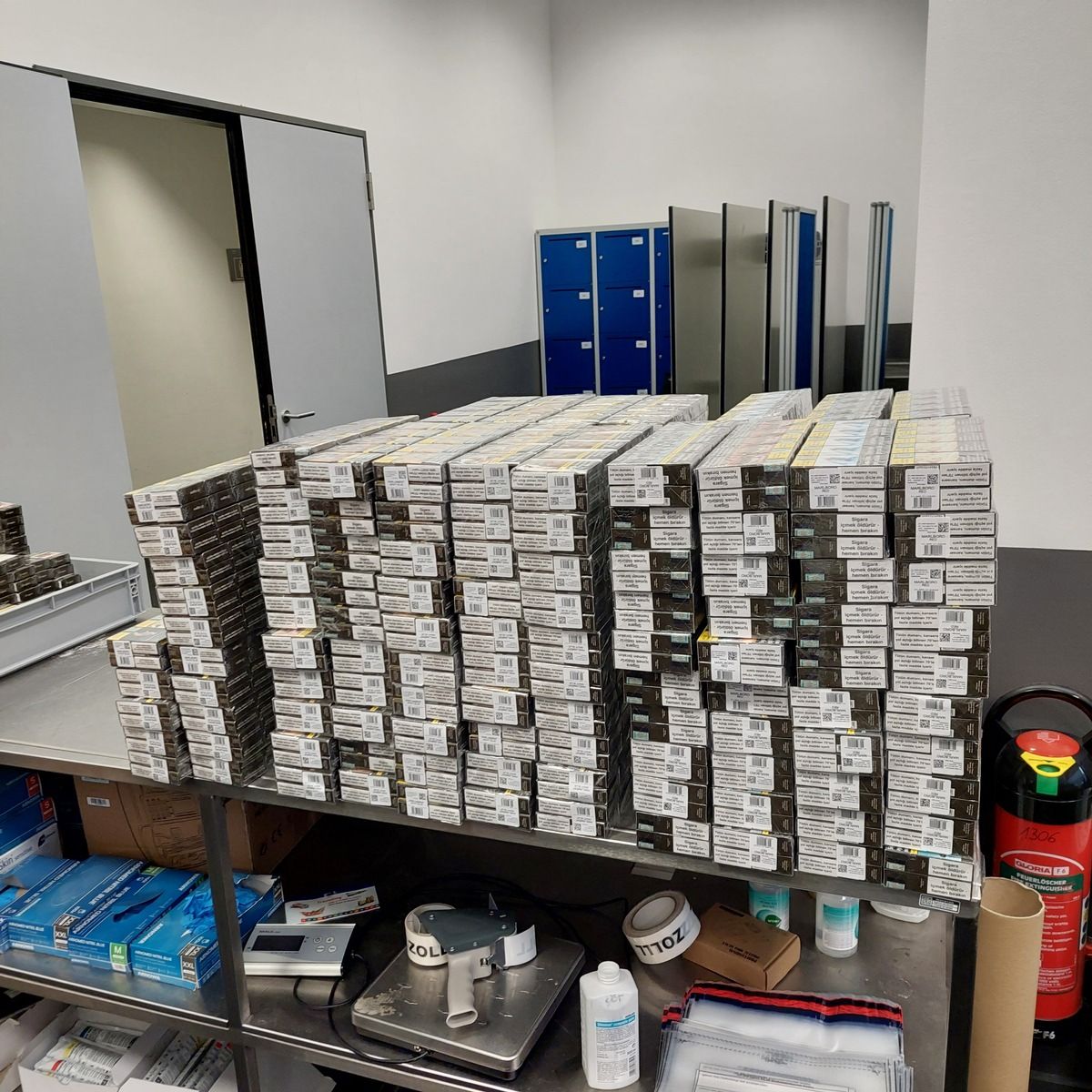 Viele Kartons mit Schmuggelzigaretten stapeln sich auf einem Tisch in einem Raum.