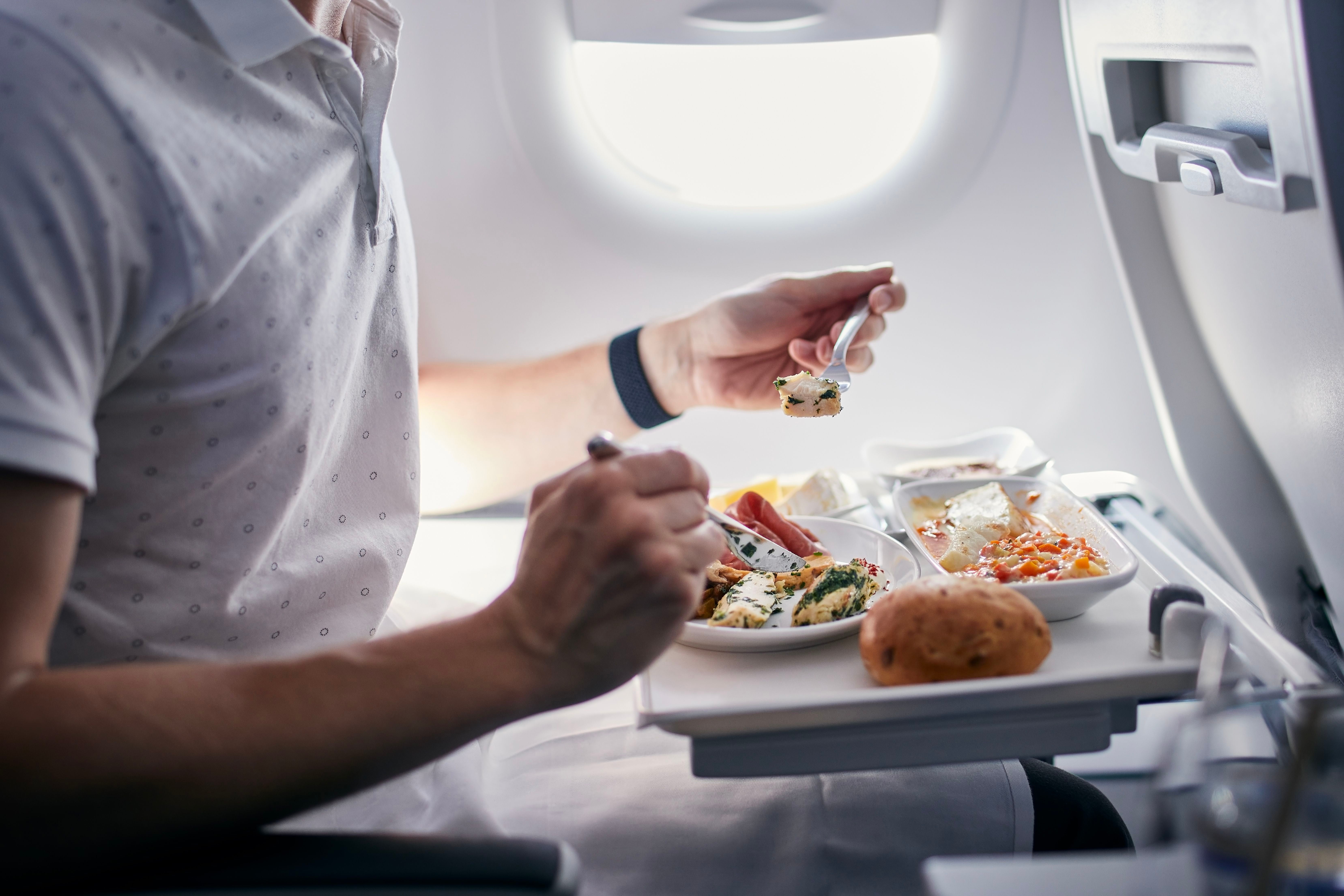 Passagier isst ein Business-Class-Menü während eines Mittelstreckenflugs im Flugzeug.