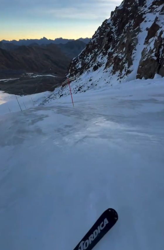 Skipiste auf einem Gletscher mit Eisschicht, ein Ski ist vorne im Bild zu sehen.