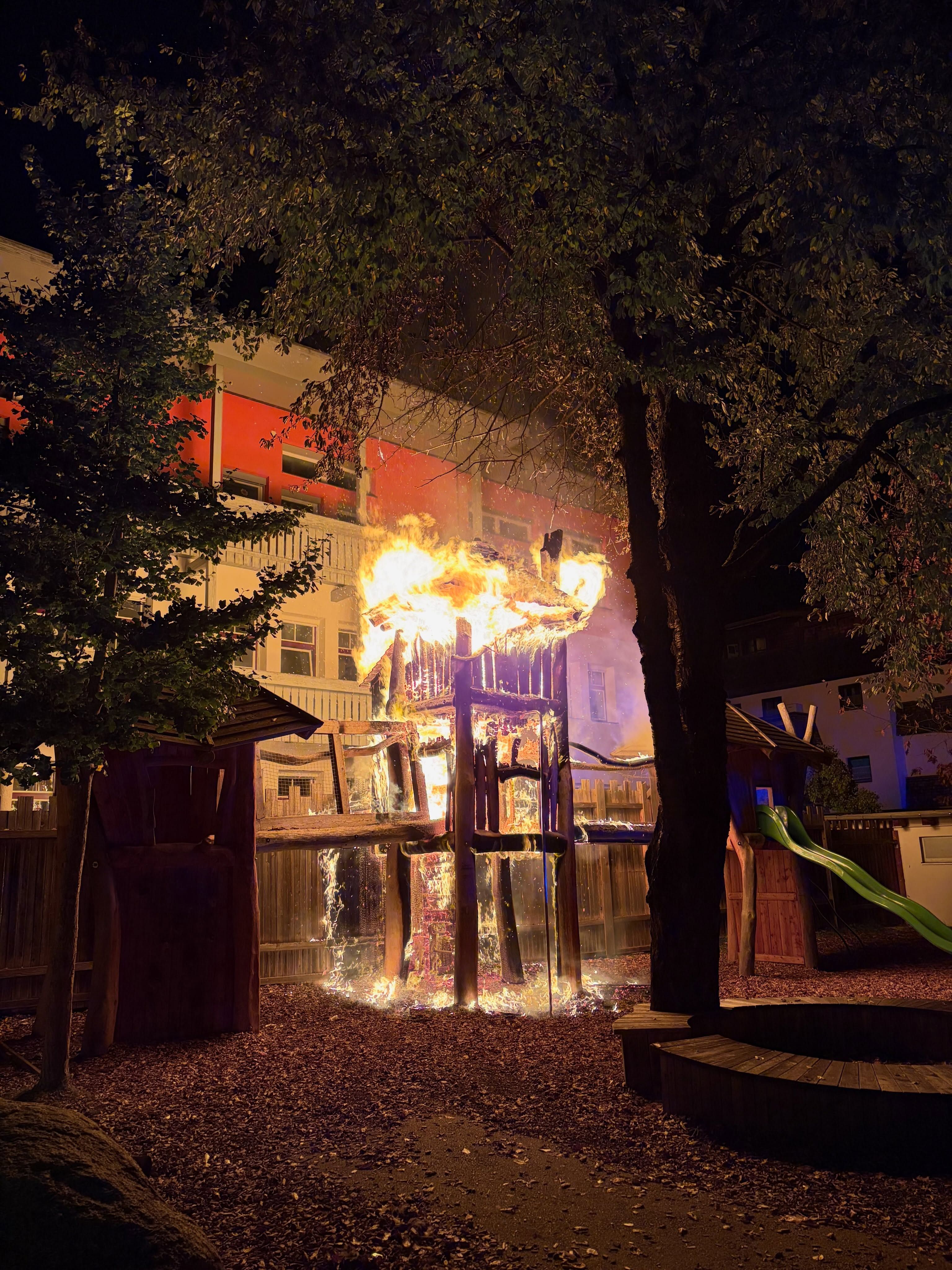 Ein hölzernes Klettergerüst auf einem Spielplatz brennt nachts in Flammen.
