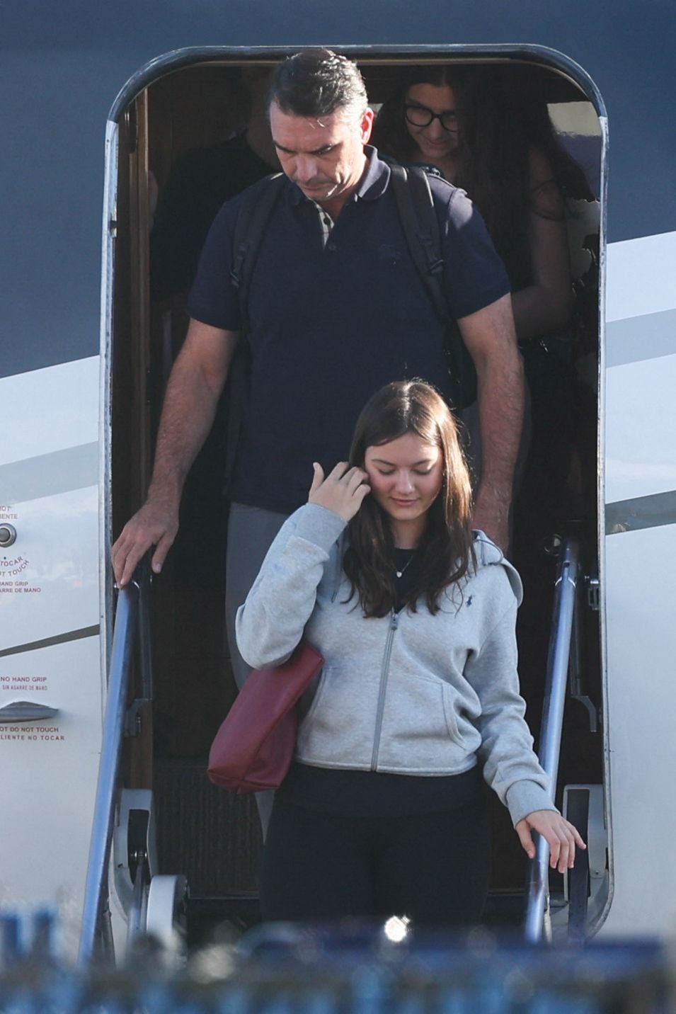 Ein Mann und eine junge Frau steigen aus einem Flugzeug und gehen die Treppe hinunter.