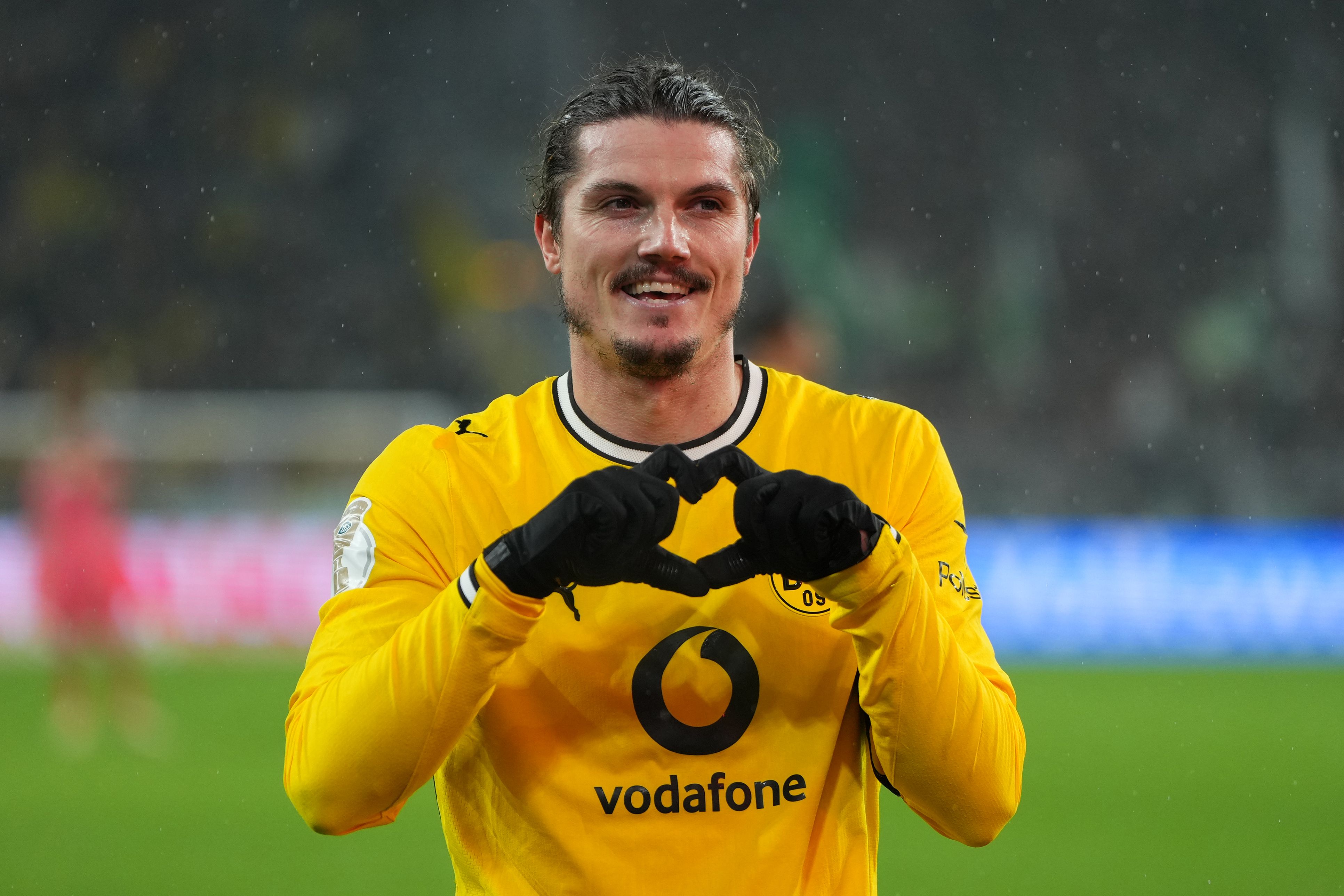 Ein Fußballspieler von Borussia Dortmund jubelt auf dem Spielfeld mit einem Herzzeichen.