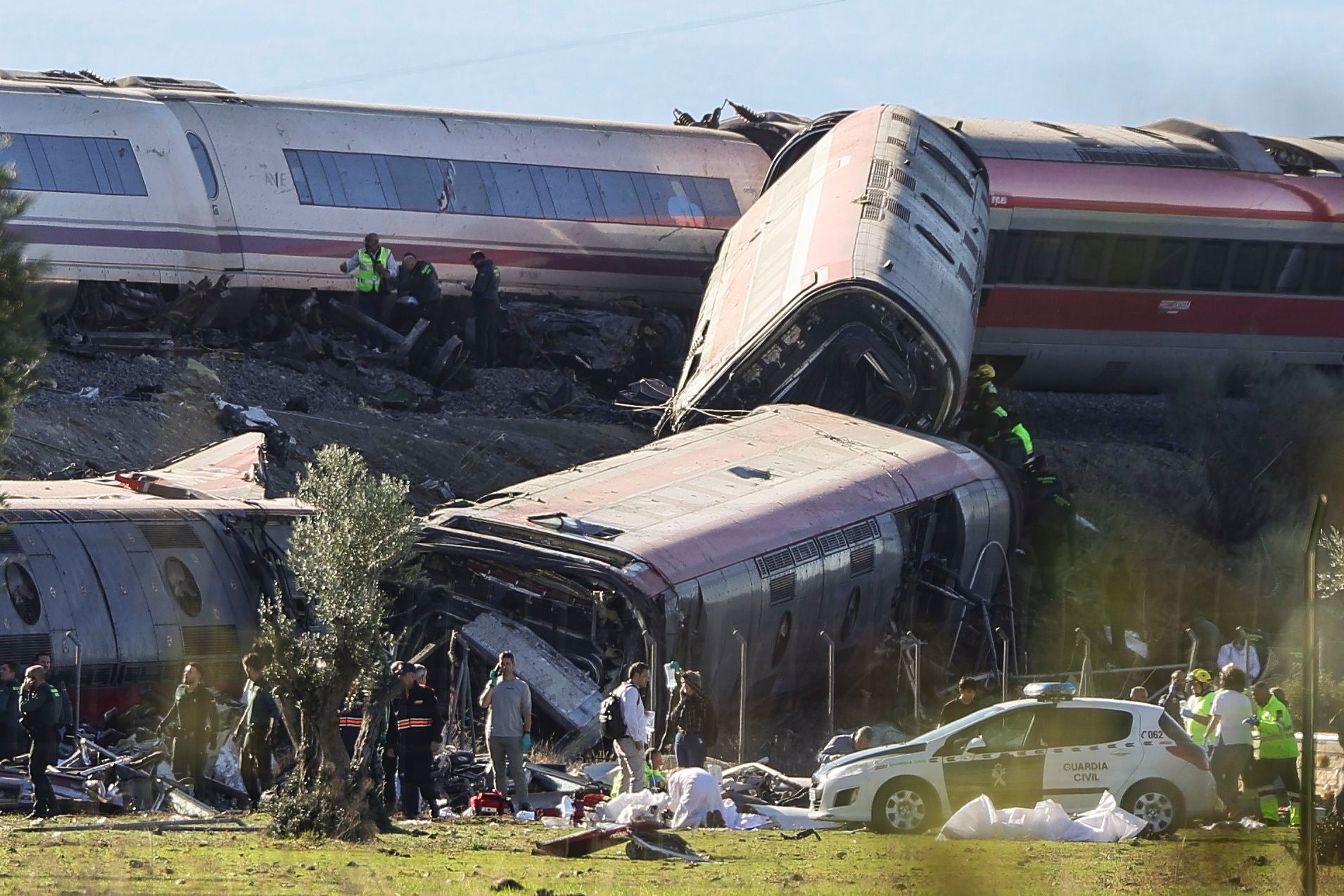 Mehrere entgleiste Hochgeschwindigkeitszüge mit Rettungskräften am Unfallort in Spanien.