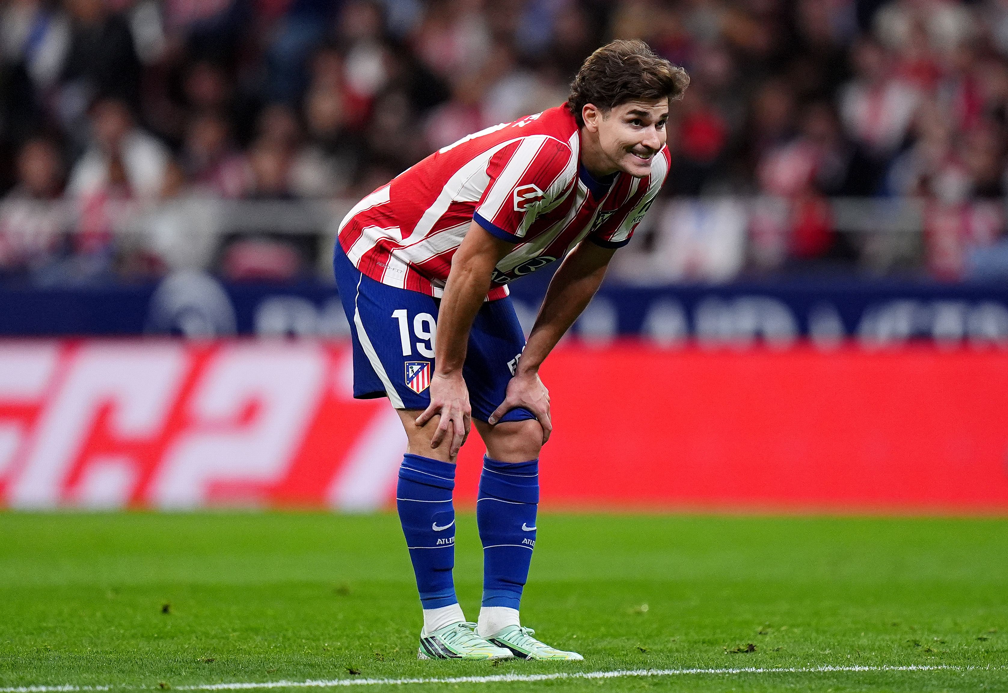 Ein Atletico-Madrid-Spieler mit Nummer 19 steht gebückt auf dem Spielfeld und schaut nach vorne.