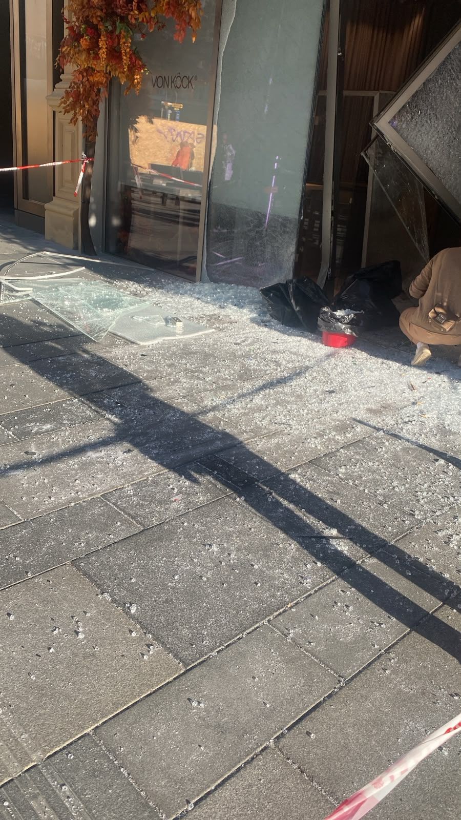 Zerbrochene Glasscheibe vor einem Juwelier, Glassplitter liegen auf dem Gehweg.