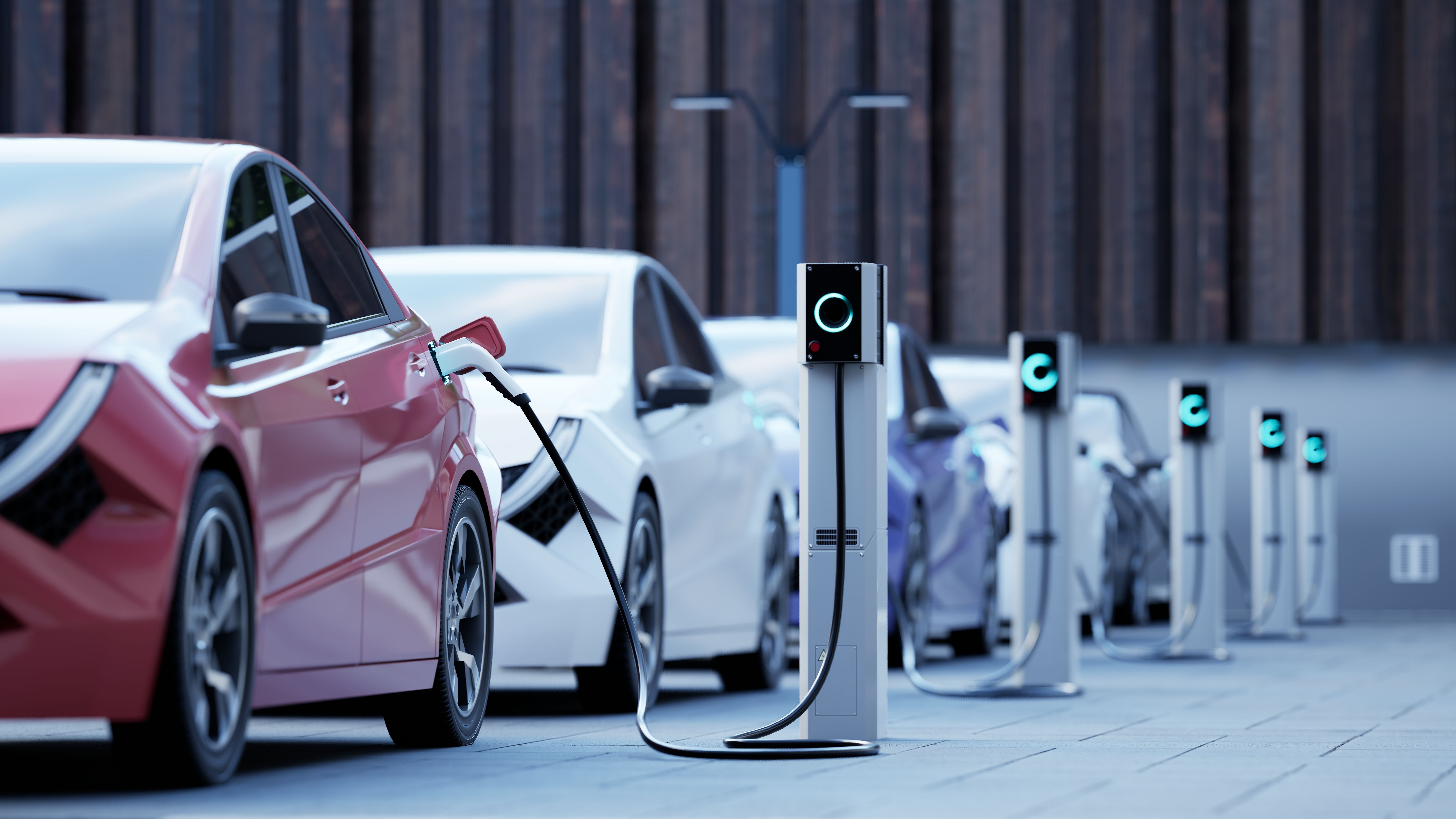 Mehrere Elektroautos laden an Ladestationen auf einer modernen Stadtstraße.