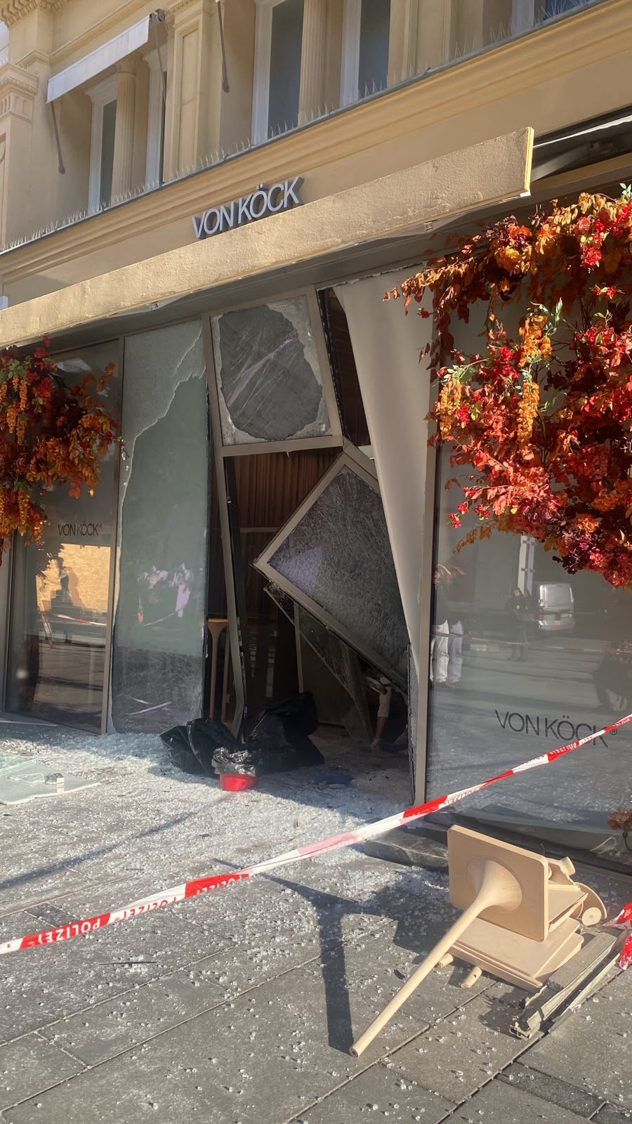 Eingeschlagene Schaufensterscheibe bei Juwelier Von Köck, Glasscherben am Boden, Absperrband.