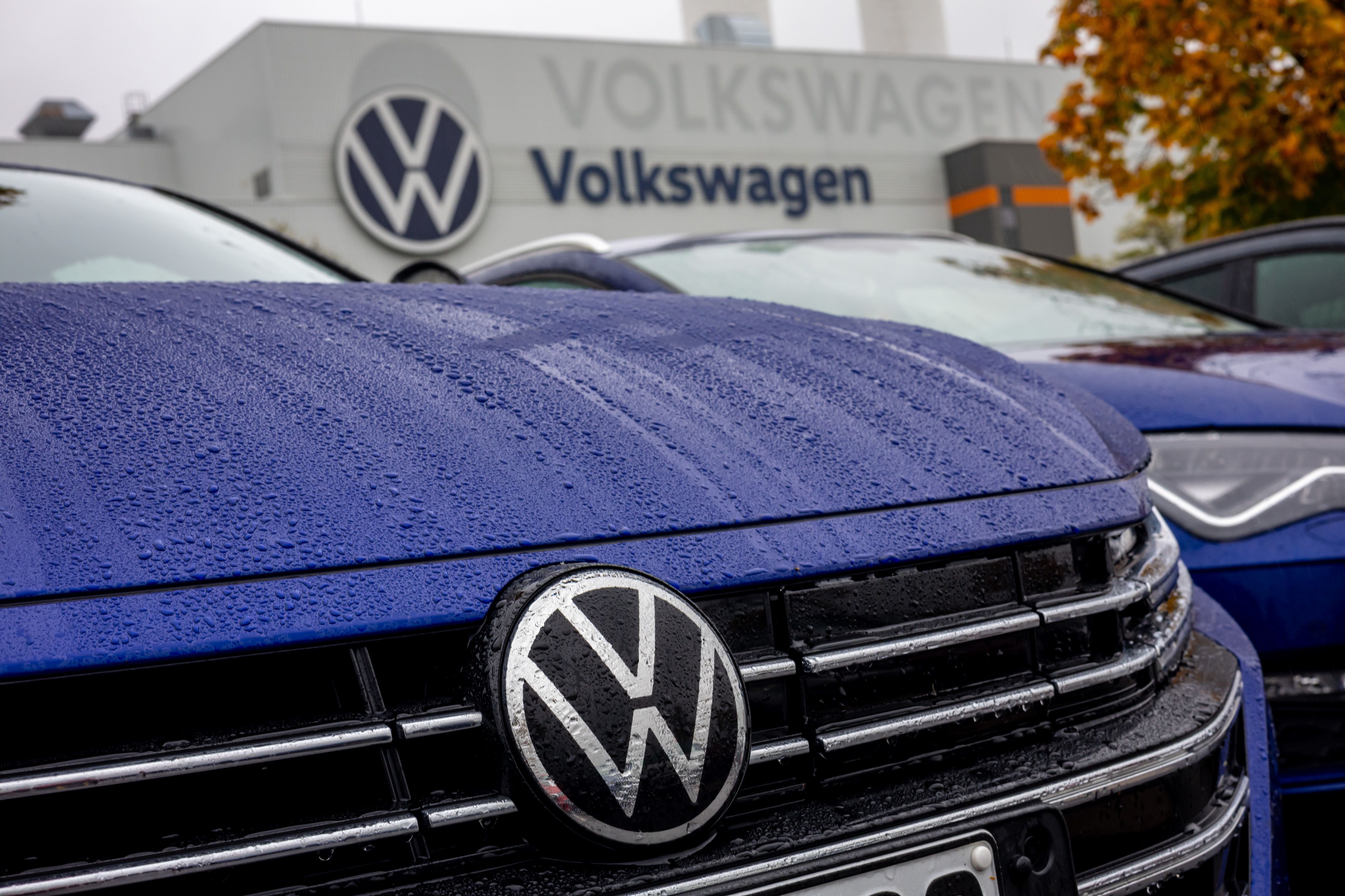 Nahaufnahme eines VW-Logos auf einem blauen Auto vor einem Volkswagen-Werk in Zwickau.