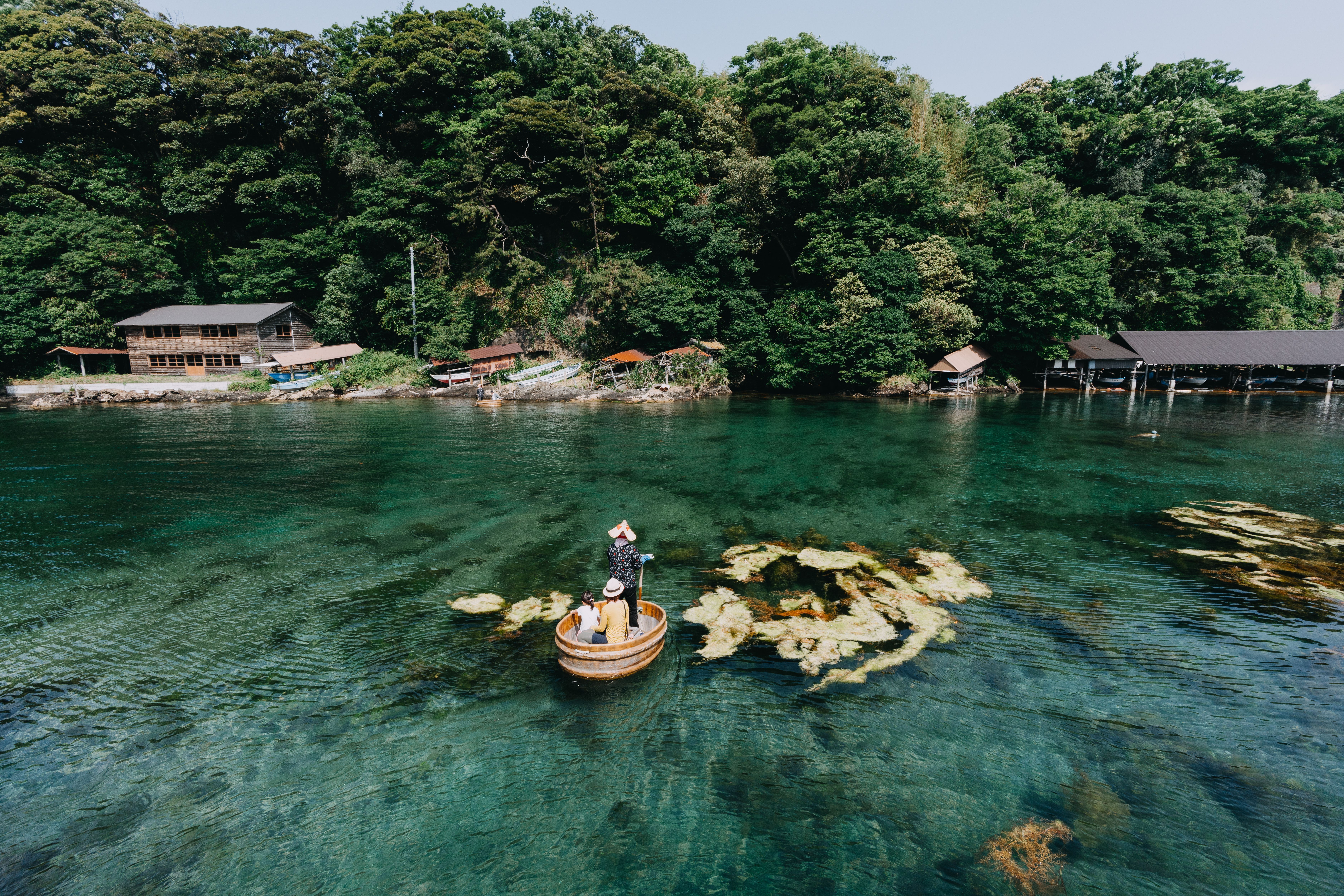 Familie fährt in einem traditionellen Wannenboot über klares Wasser auf Sado-Insel, Japan.