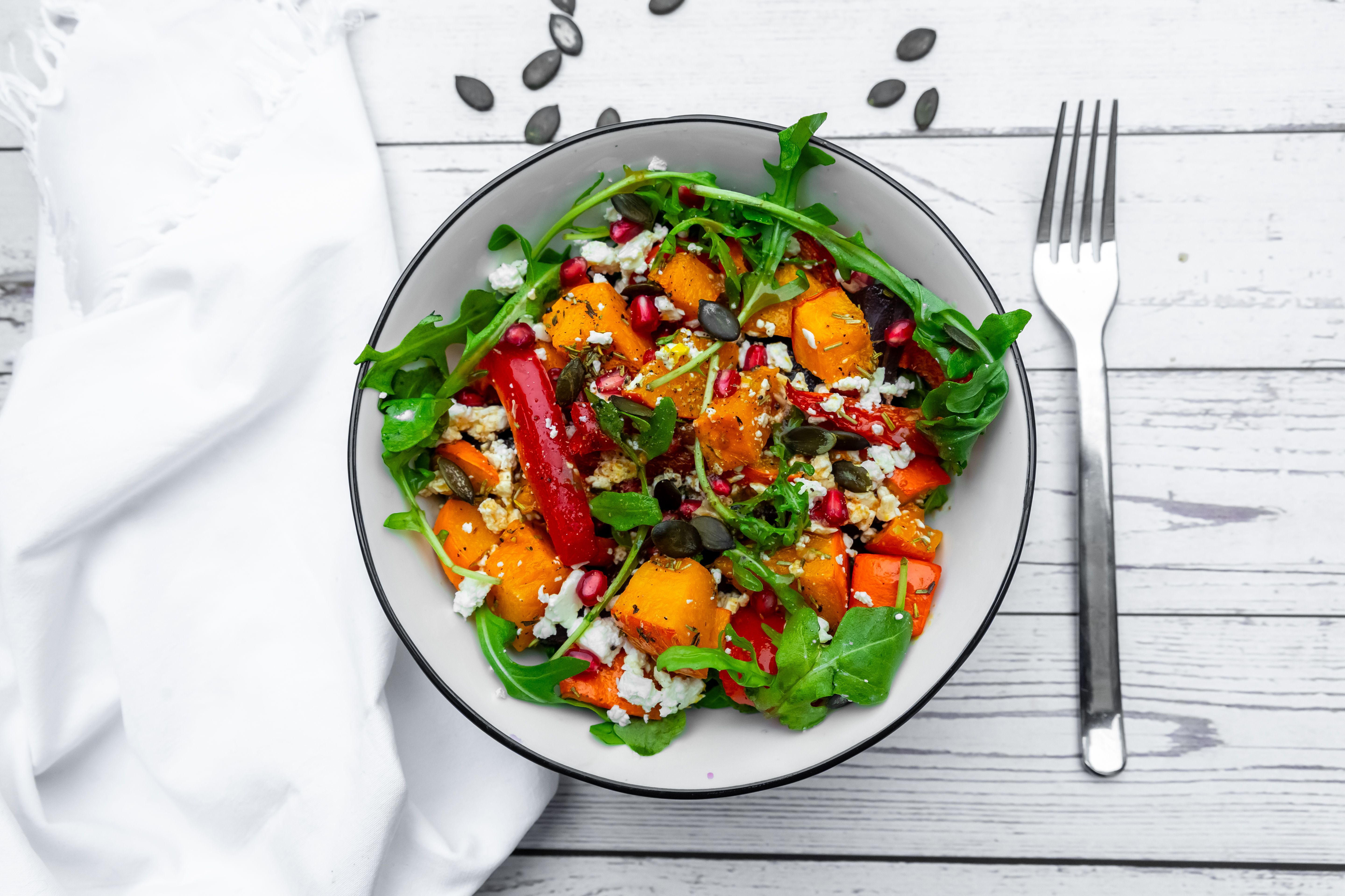 Bunter Salat mit Kürbis, Rucola, Paprika, Käse, Granatapfelkernen und Kürbiskernen.