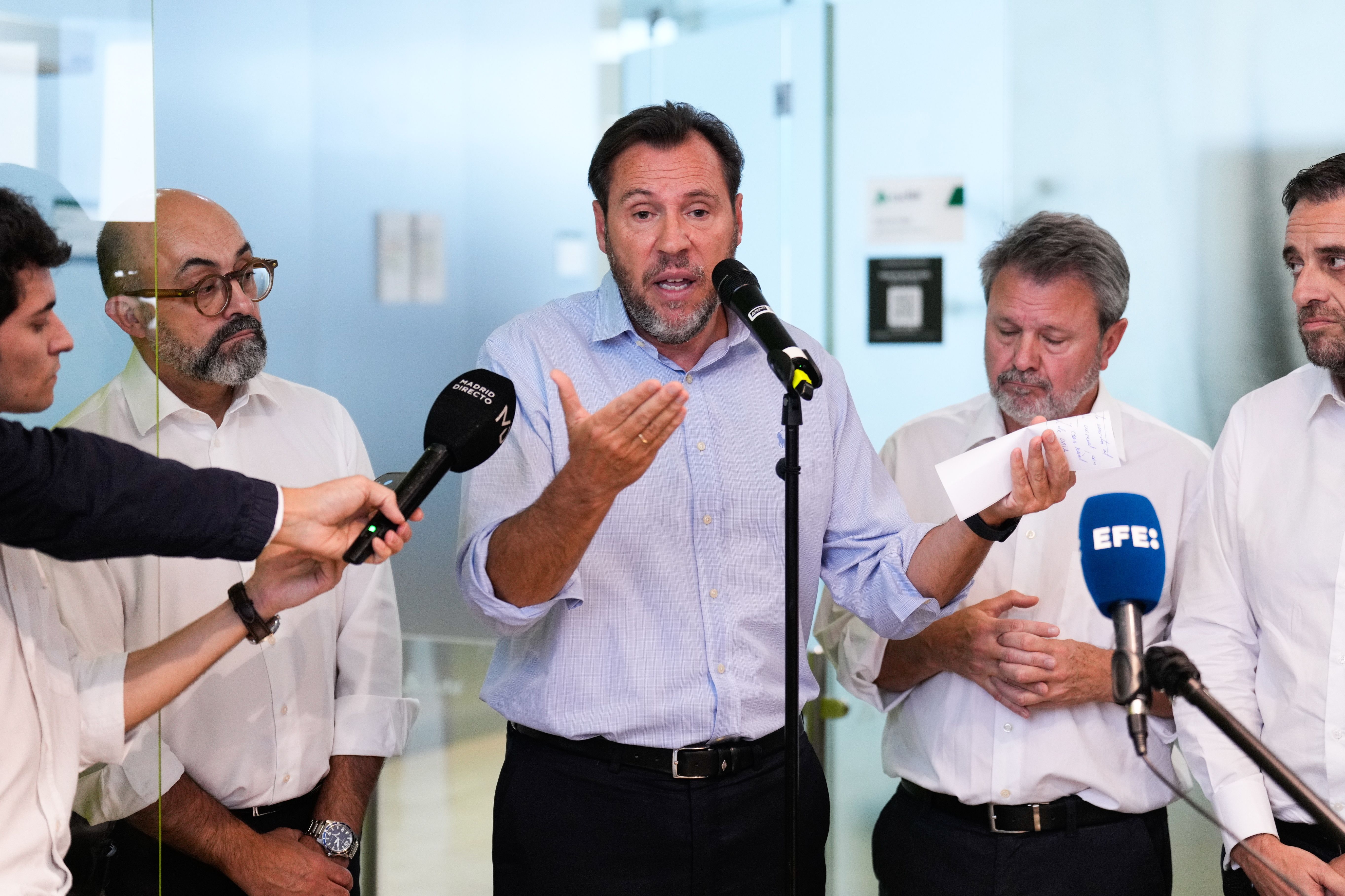 Ein Mann spricht bei einer Pressekonferenz, Mikrofone sind auf ihn gerichtet.