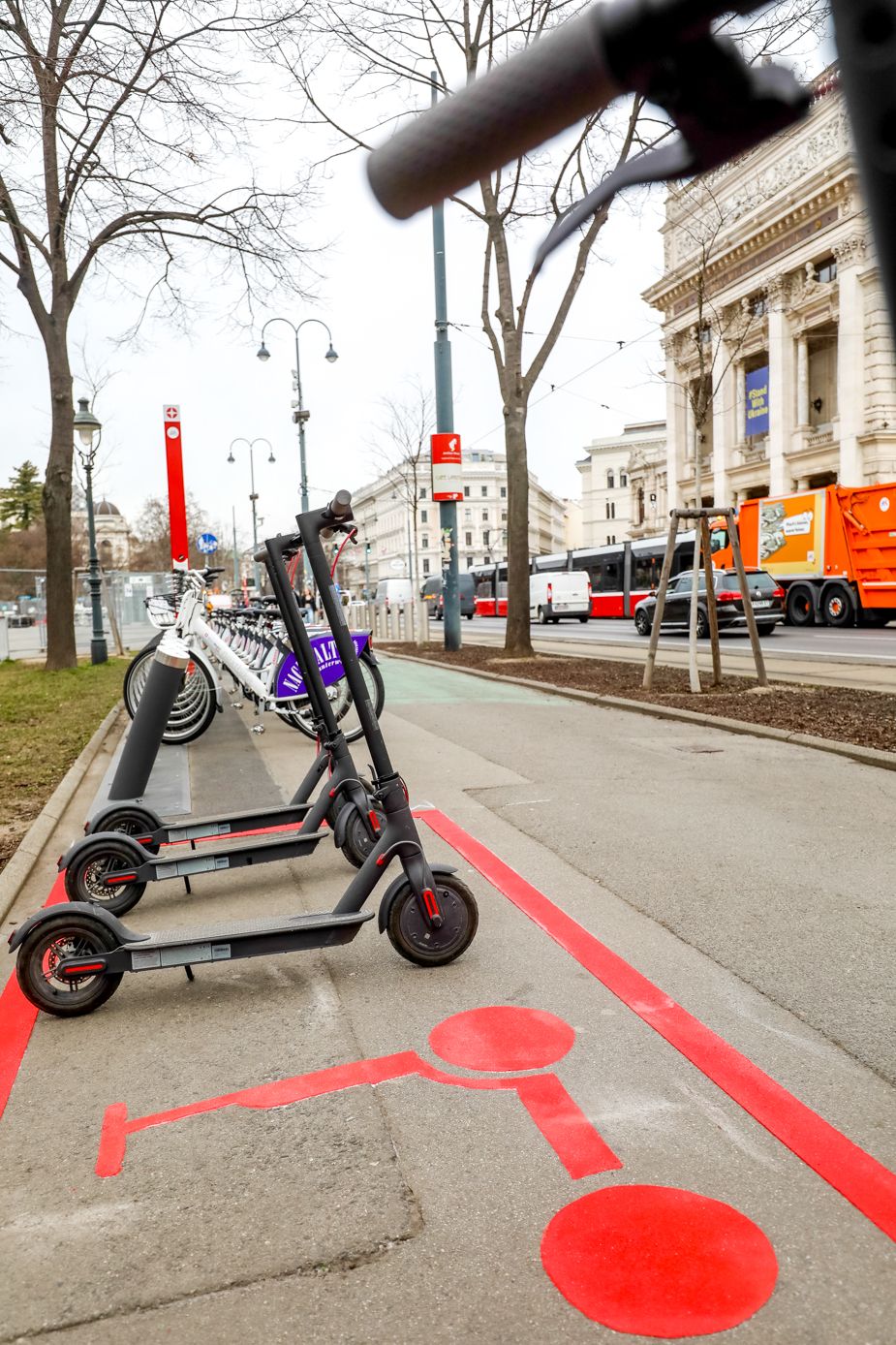 E-Scooter stehen ordentlich auf markiertem Parkplatz am Straßenrand in urbaner Umgebung.