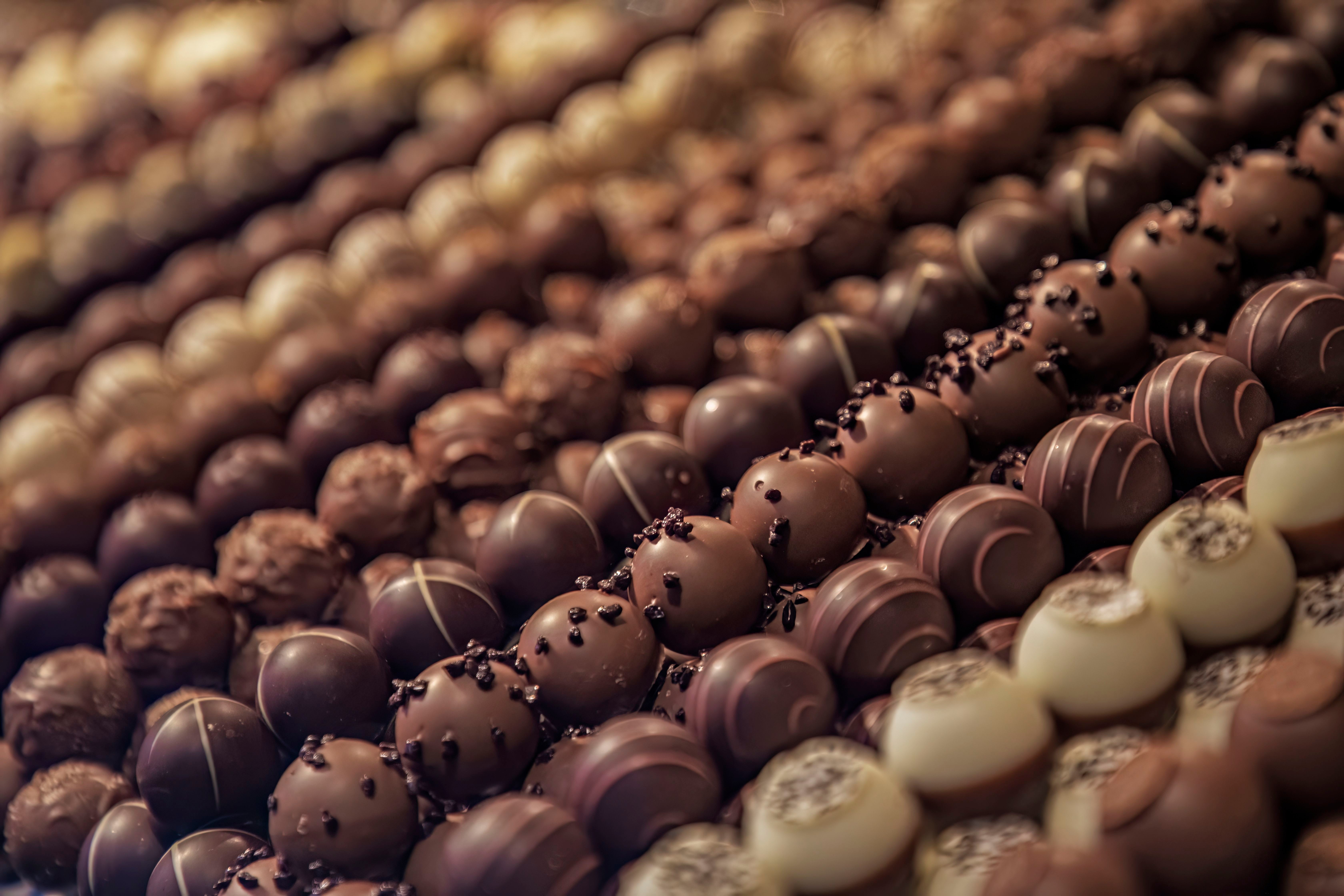 Verschiedene Sorten Schokoladenpralinen sind in Reihen nebeneinander angerichtet.