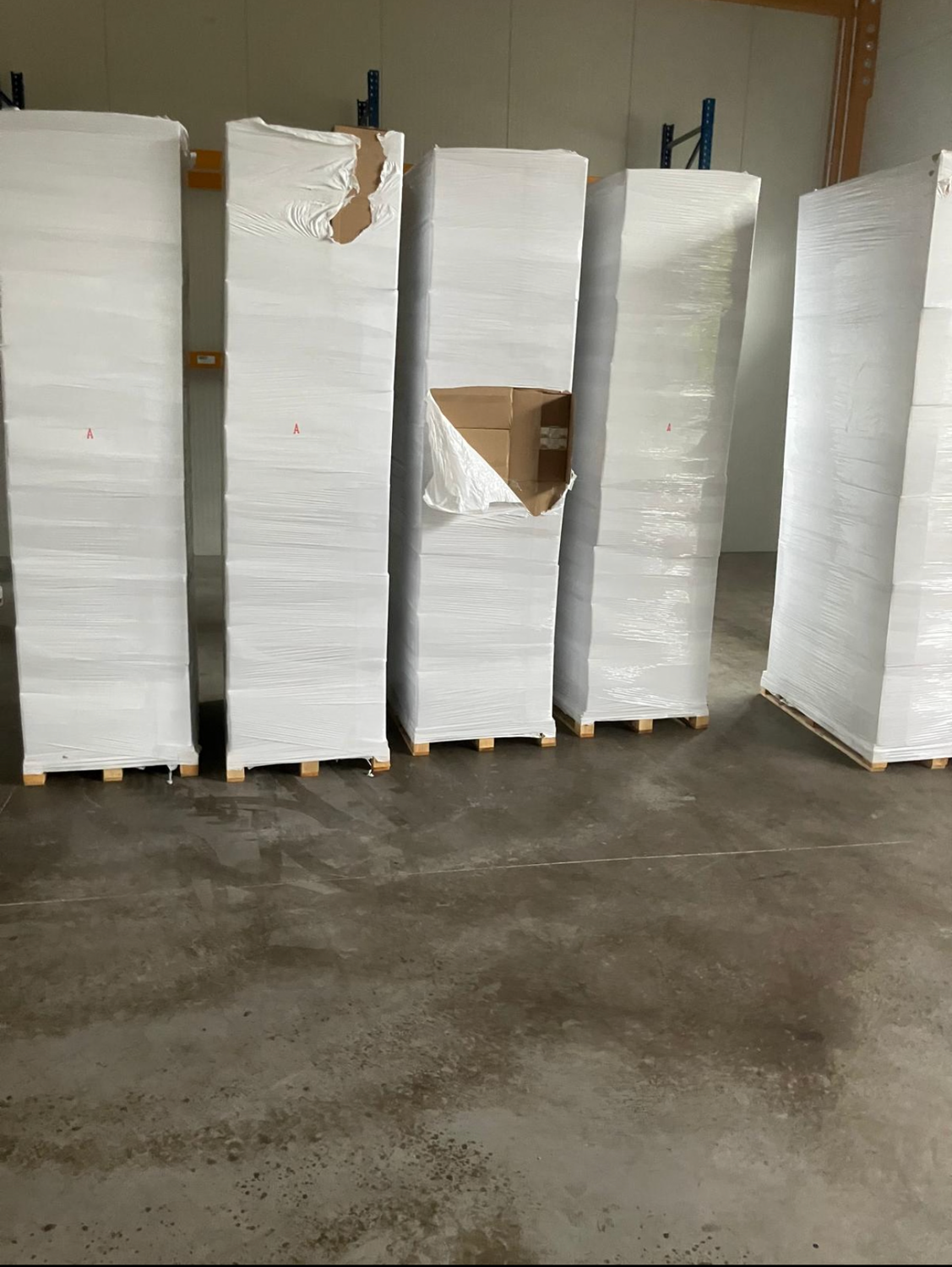 Mehrere in Folie verpackte Paletten, zwei davon mit großen Rissen in der Folie.