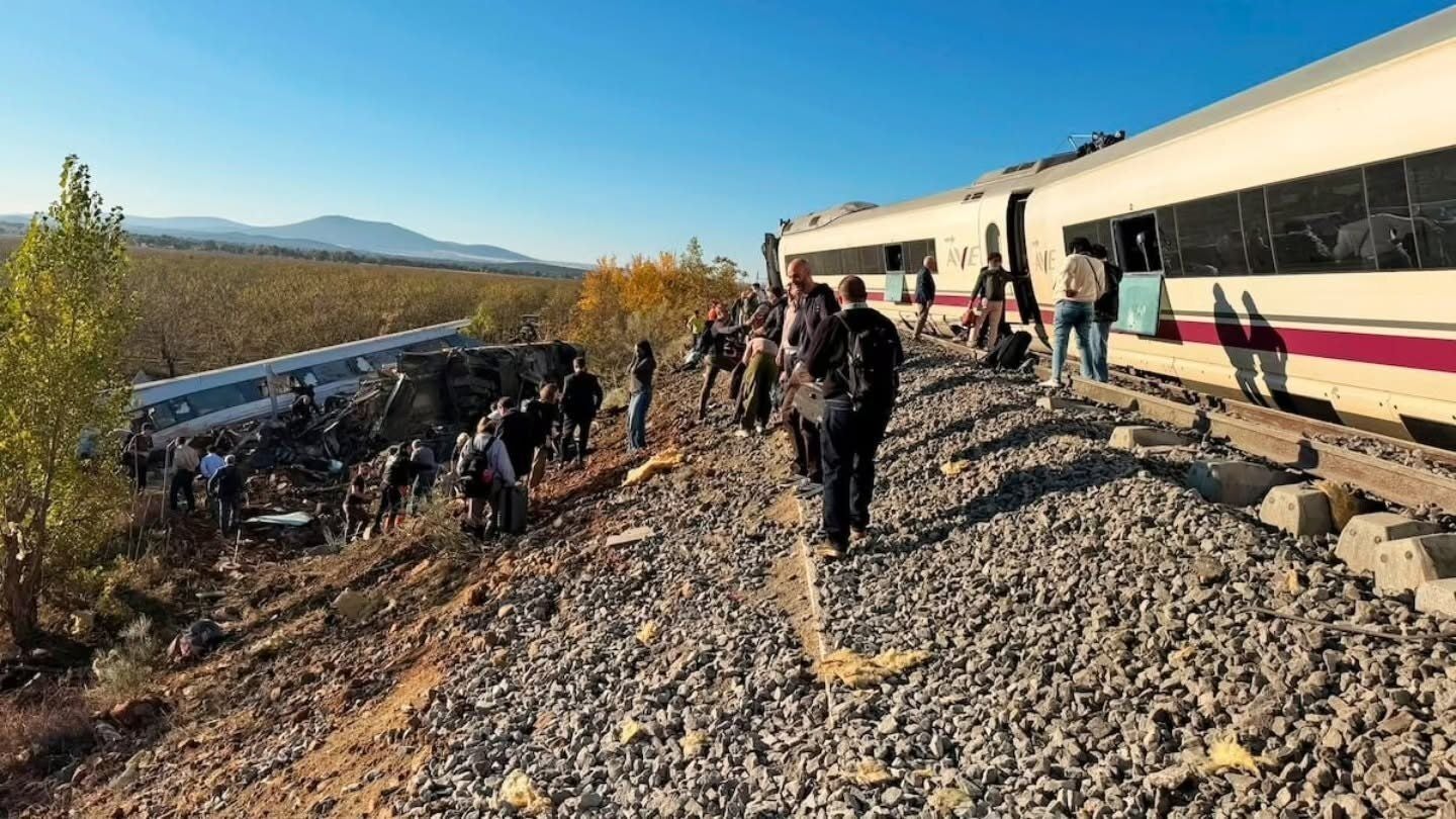 Menschen verlassen beschädigte Hochgeschwindigkeitszüge nach einem Zugunglück auf Gleisschotter in Spanien.