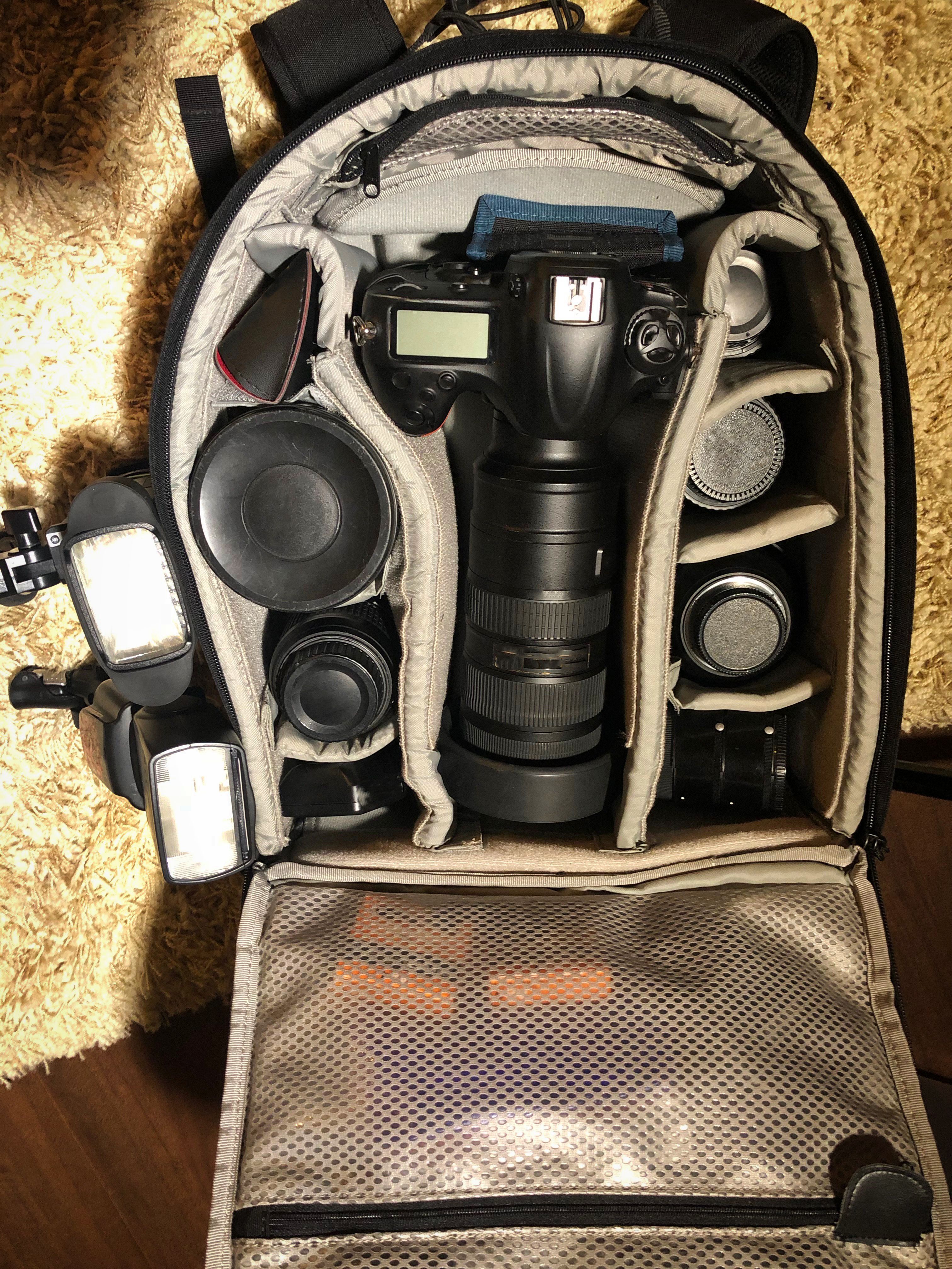 Fotorucksack mit DSLR-Kamera, Objektiven und Blitzgeräten in separaten Fächern.