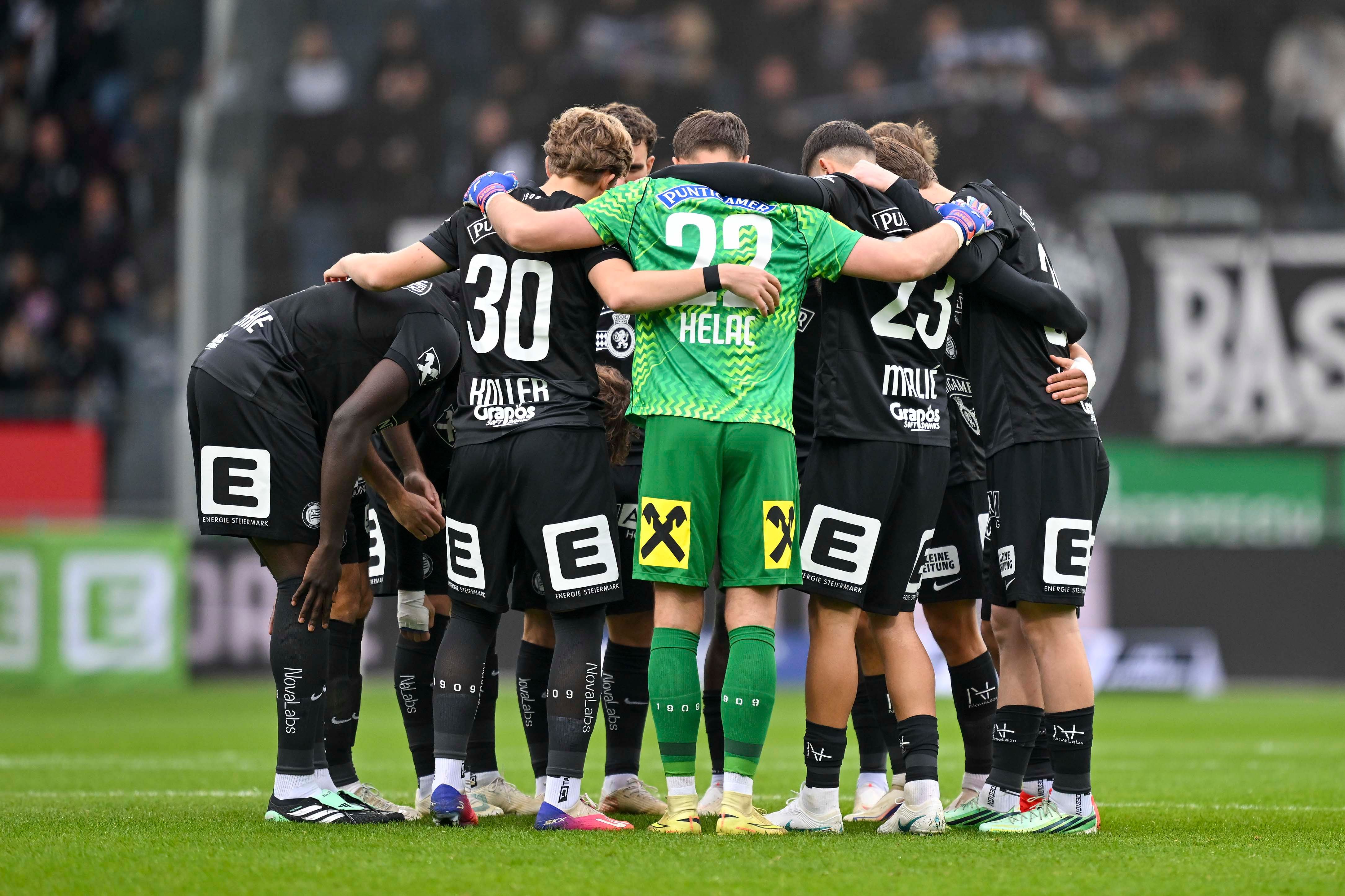 Fußballspieler von Sturm Graz stehen im Kreis und umarmen sich vor dem Spiel.