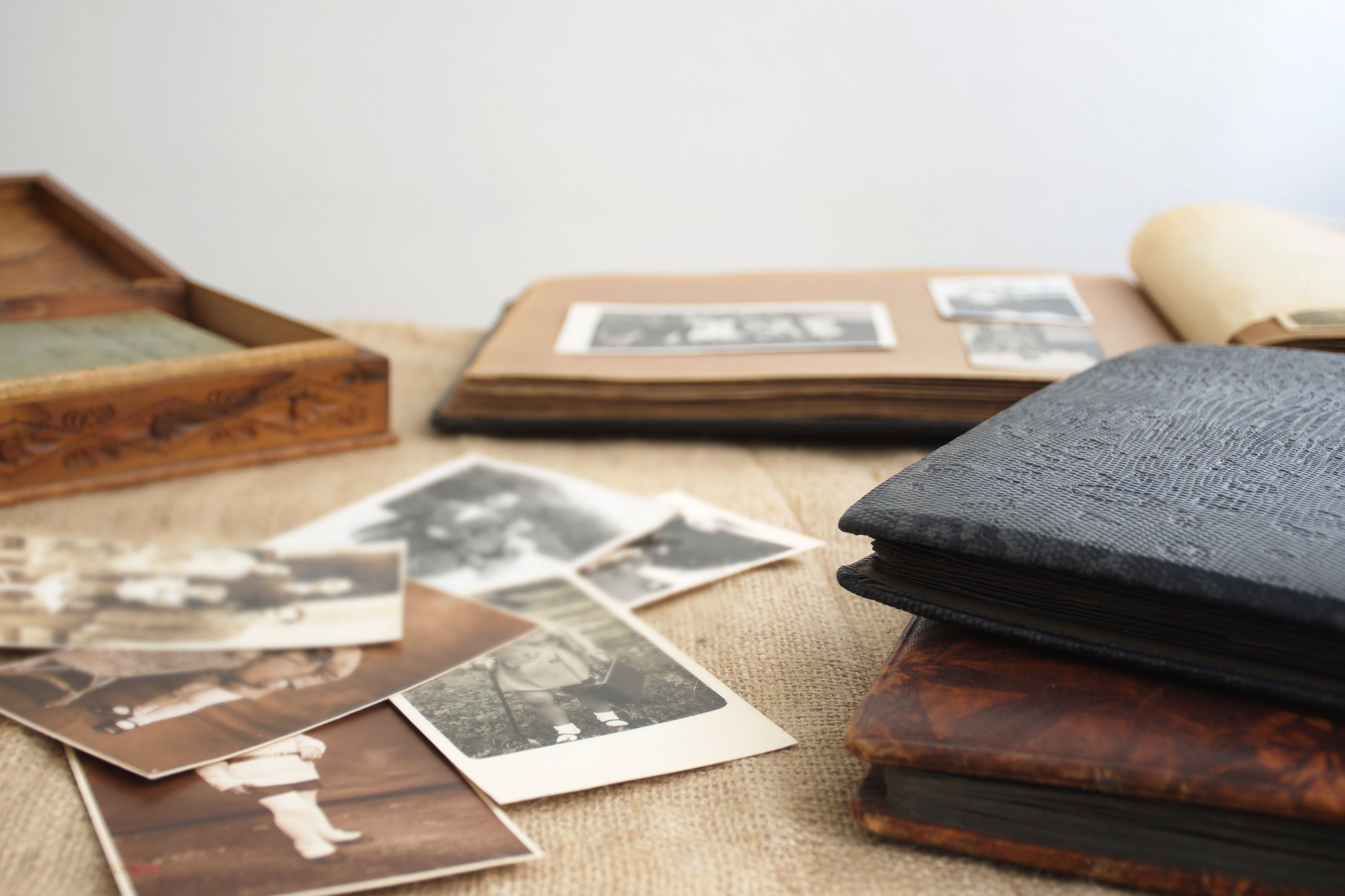 Alte Fotoalben und mehrere vintage Schwarz-Weiß-Fotos liegen auf einem Tisch.