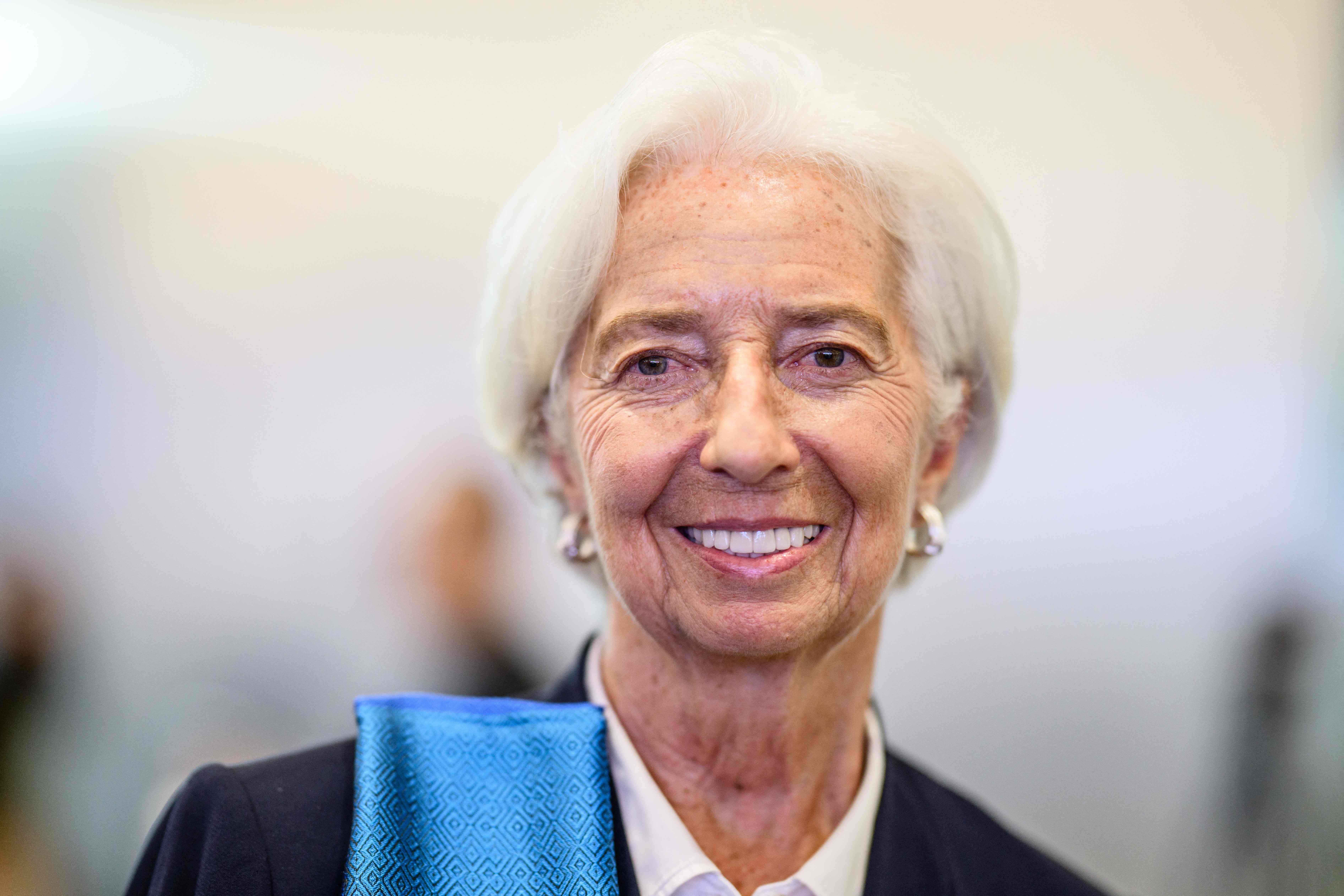 Eine ältere Frau mit weißem Haar lächelt in die Kamera, formell gekleidet.