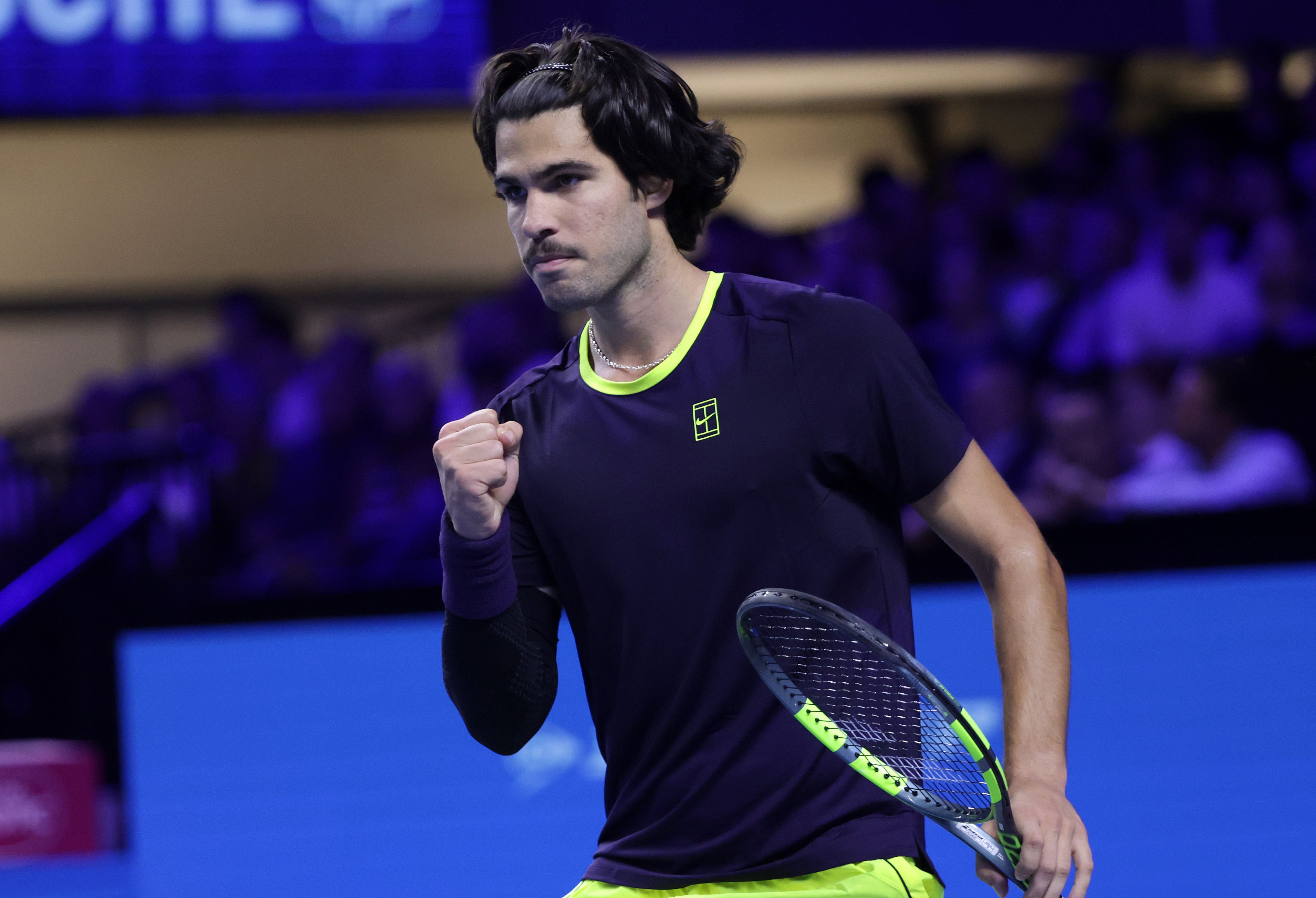Ein Tennisspieler jubelt mit geballter Faust auf einem Hallenplatz während eines Matches.