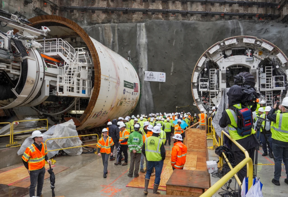 Viele Bauarbeiter stehen vor einem riesigen Tunnelbohrer auf einer Baustelle in Manhattan.