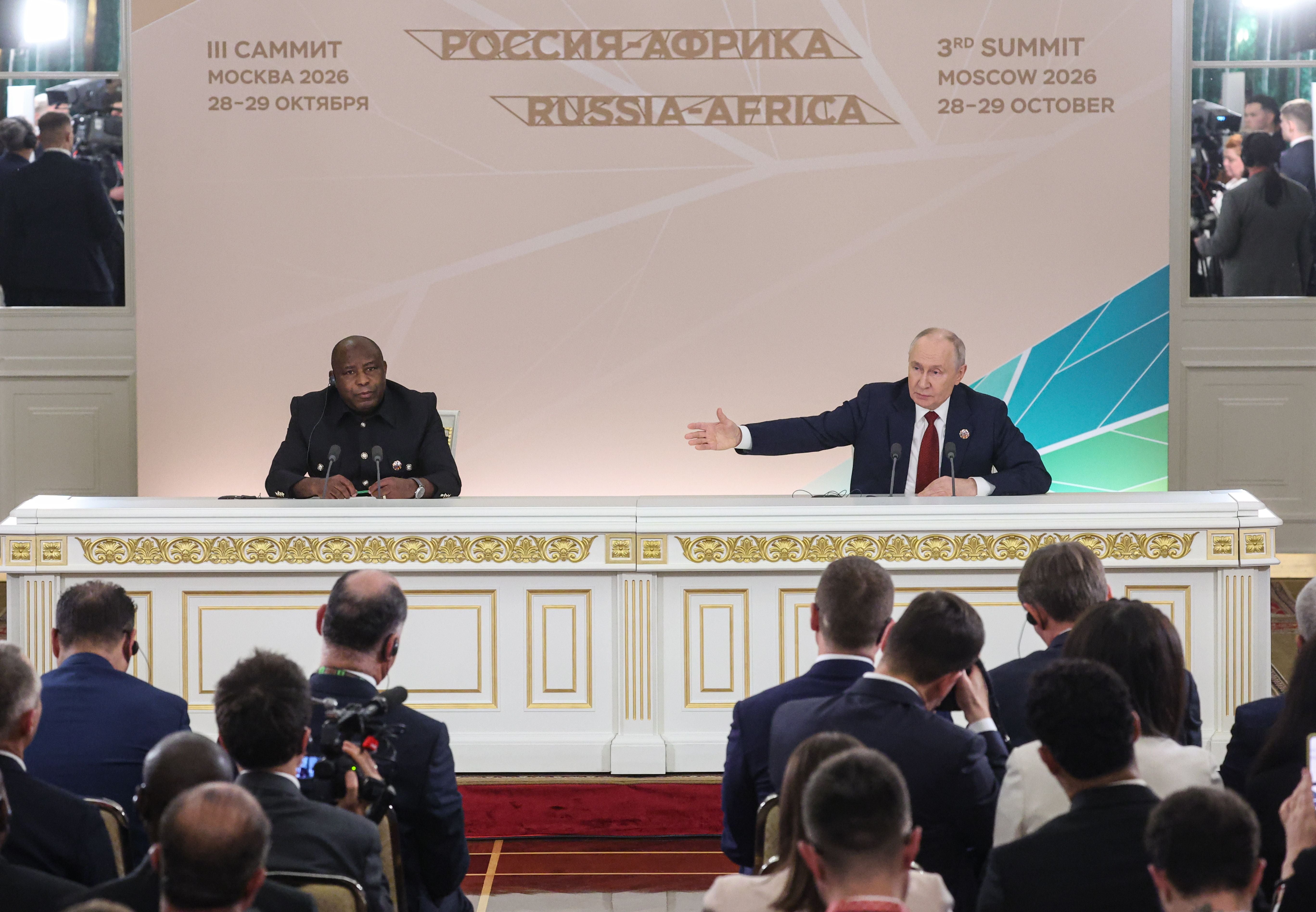 Zwei Politiker sitzen bei einer Pressekonferenz beim Russland-Afrika-Gipfel in Moskau vor Publikum.