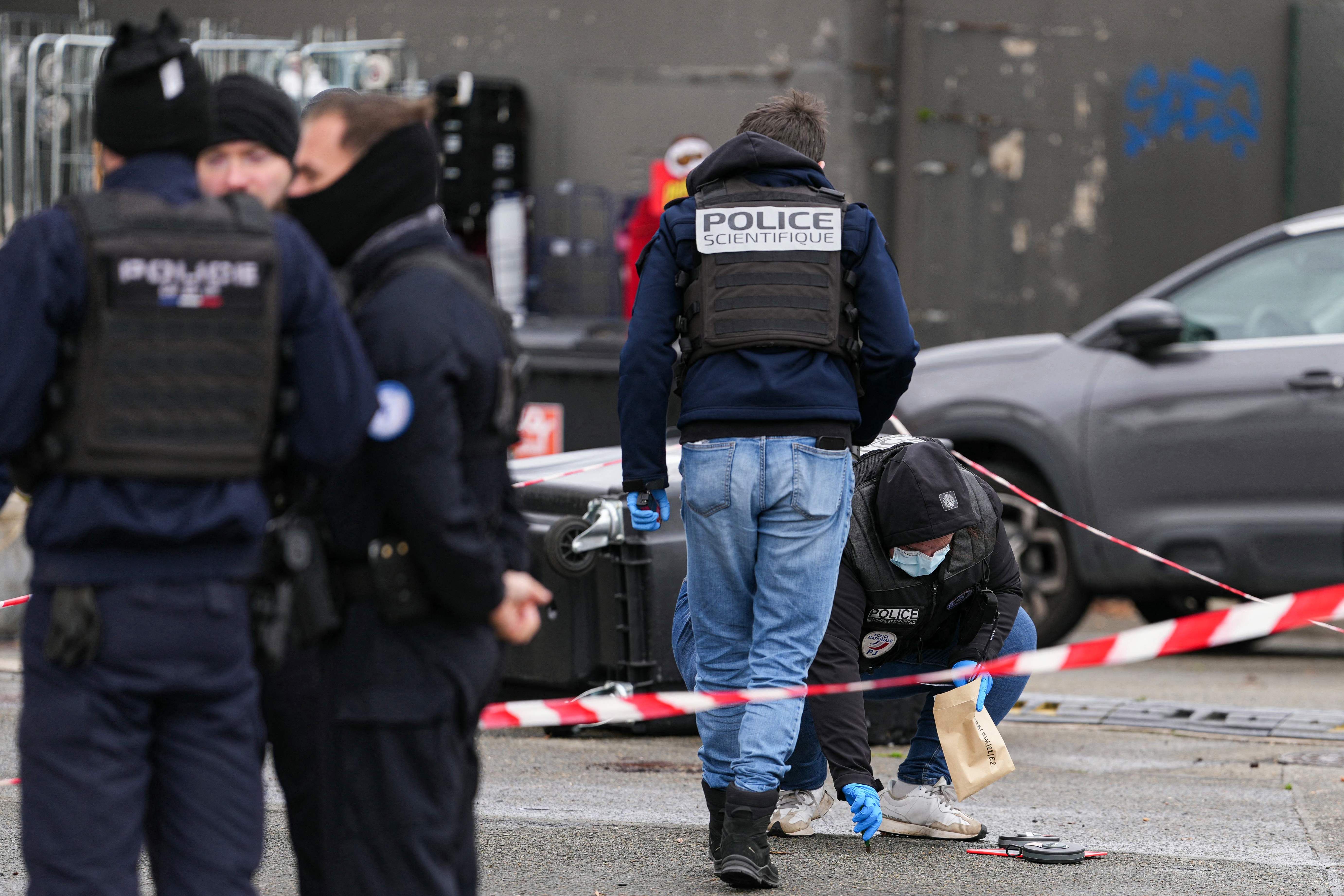 Mehrere Polizisten sichern einen abgesperrten Tatort neben einer Straße und einem Fahrzeug.