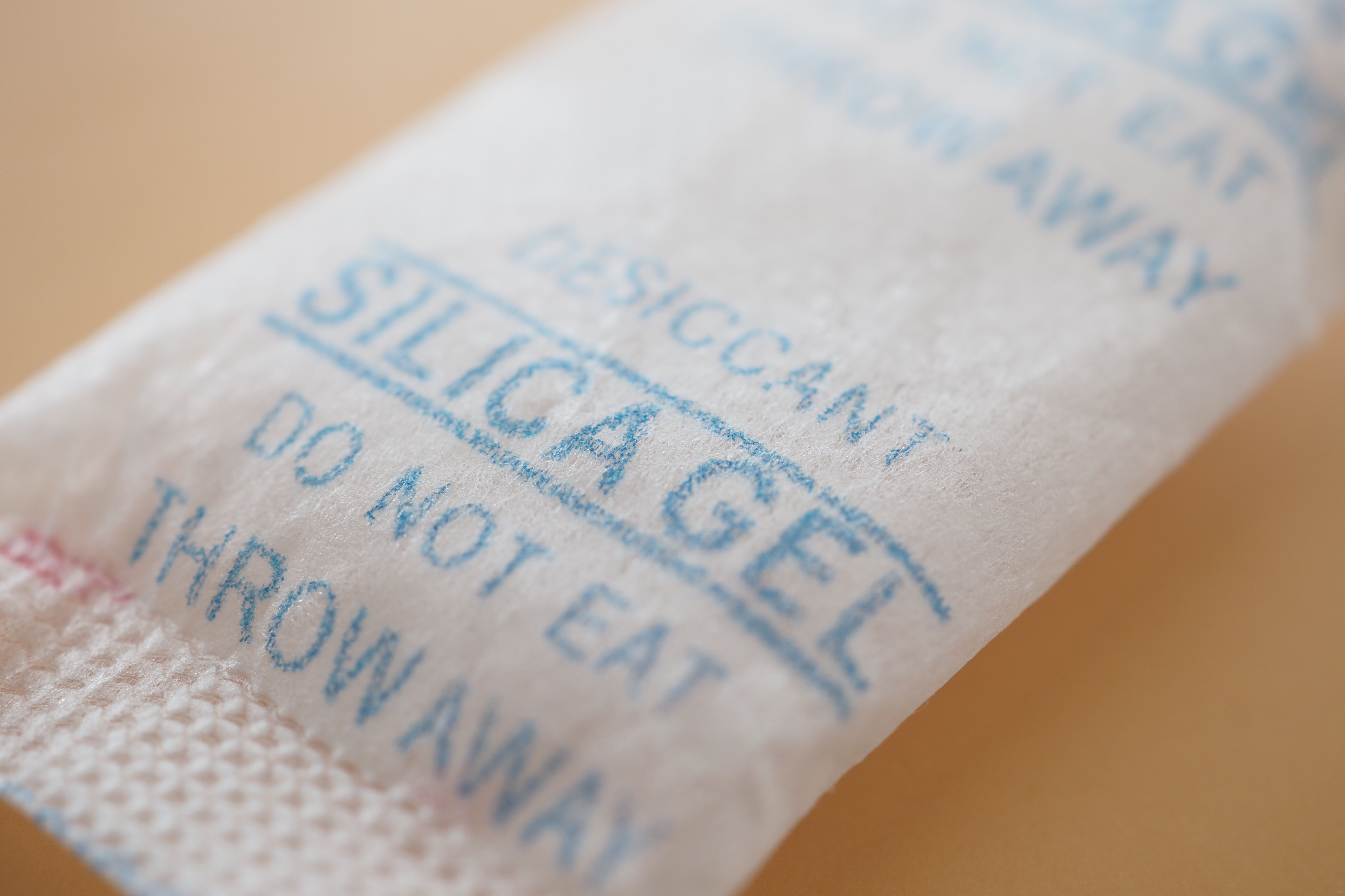Nahaufnahme eines Silica-Gel-Beutels mit der Aufschrift „Do not eat“ auf einem Tisch.