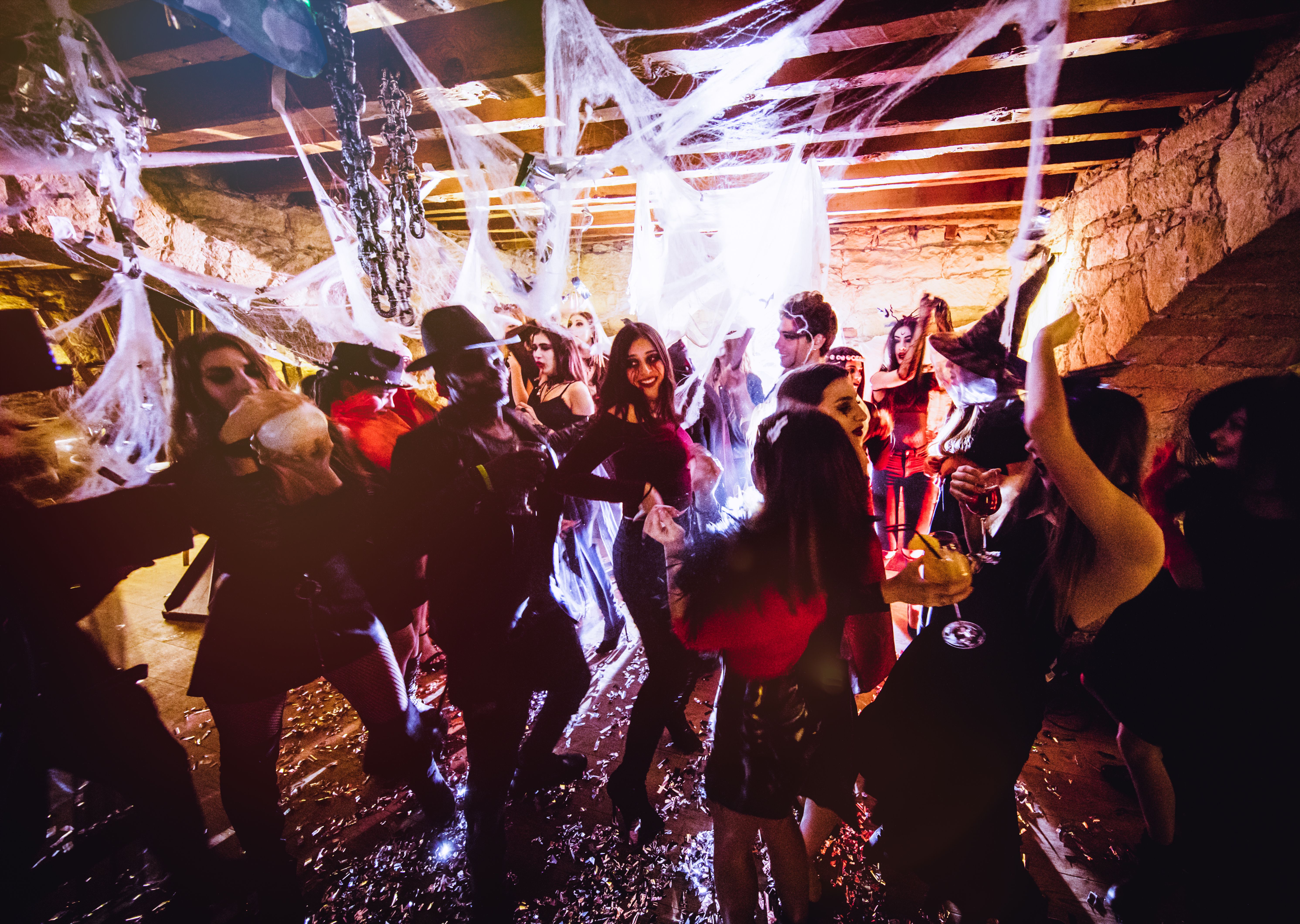 Junge Leute in Halloween-Kostümen tanzen und feiern in einer dekorierten Partylocation.
