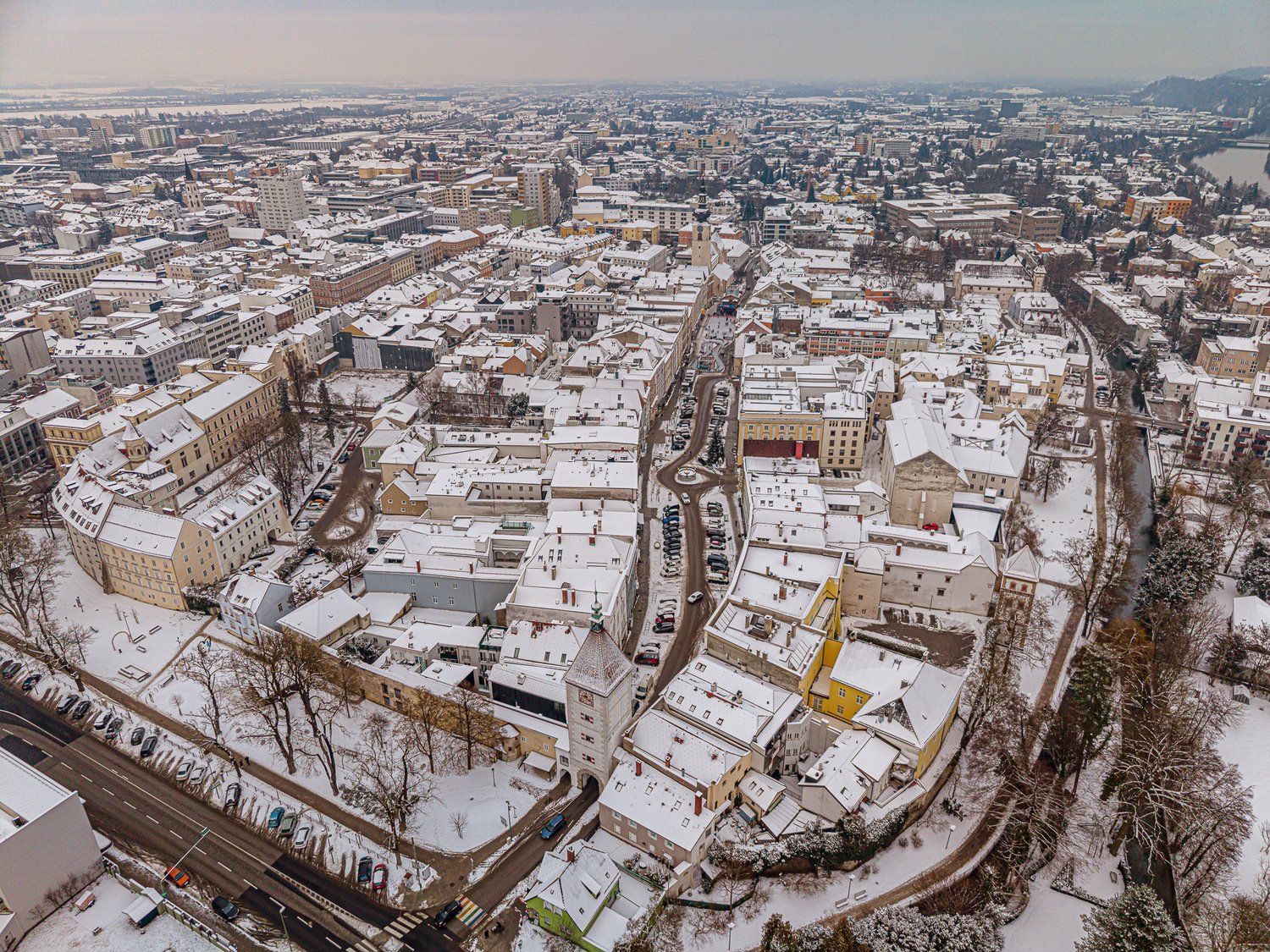Luftaufnahme von Wels im Winter mit schneebedeckten Häusern und Straßen.