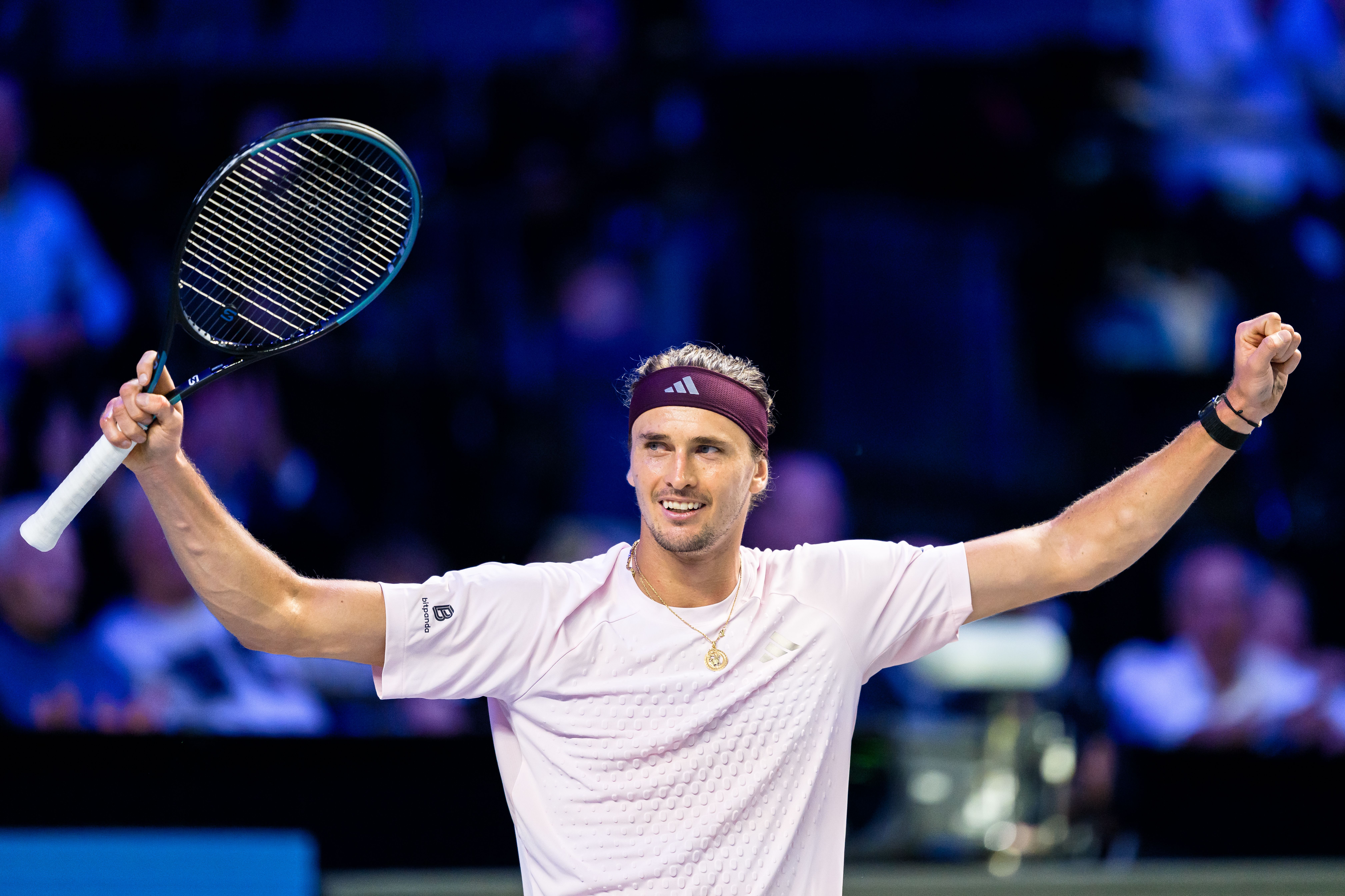 Alexander Zverev jubelt mit erhobenem Schläger und geballter Faust im hellrosa Trikot auf dem Tennisplatz.