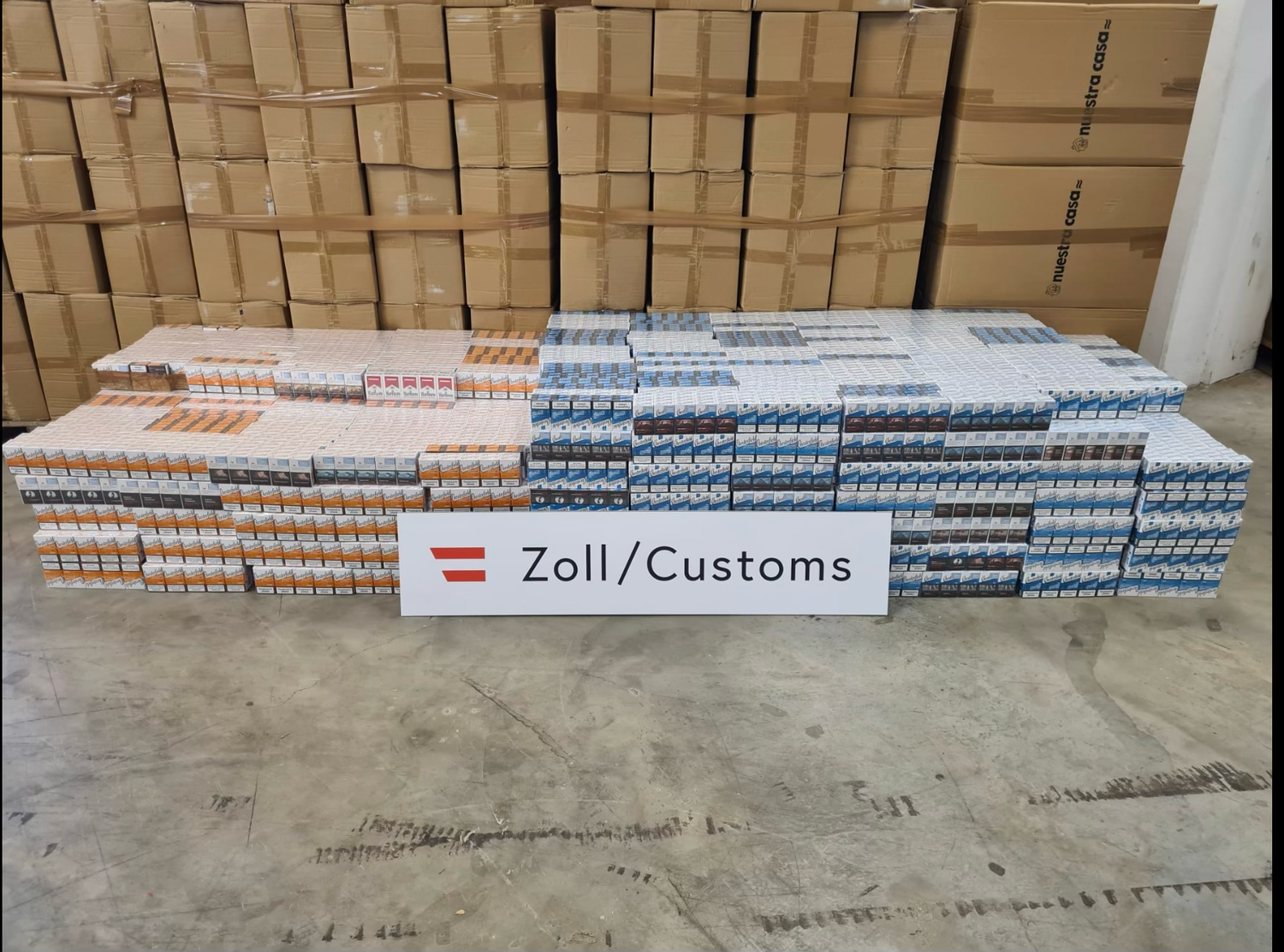 Viele Kartons mit geschmuggelten Zigaretten, davor ein Schild mit "Zoll/Customs".