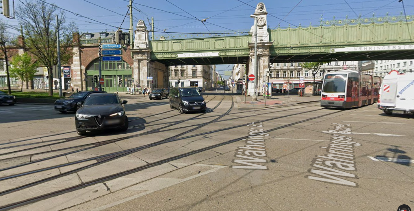 Kreuzung mit Autos, Straßenbahn und Brücke über der Währinger Straße in Wien.