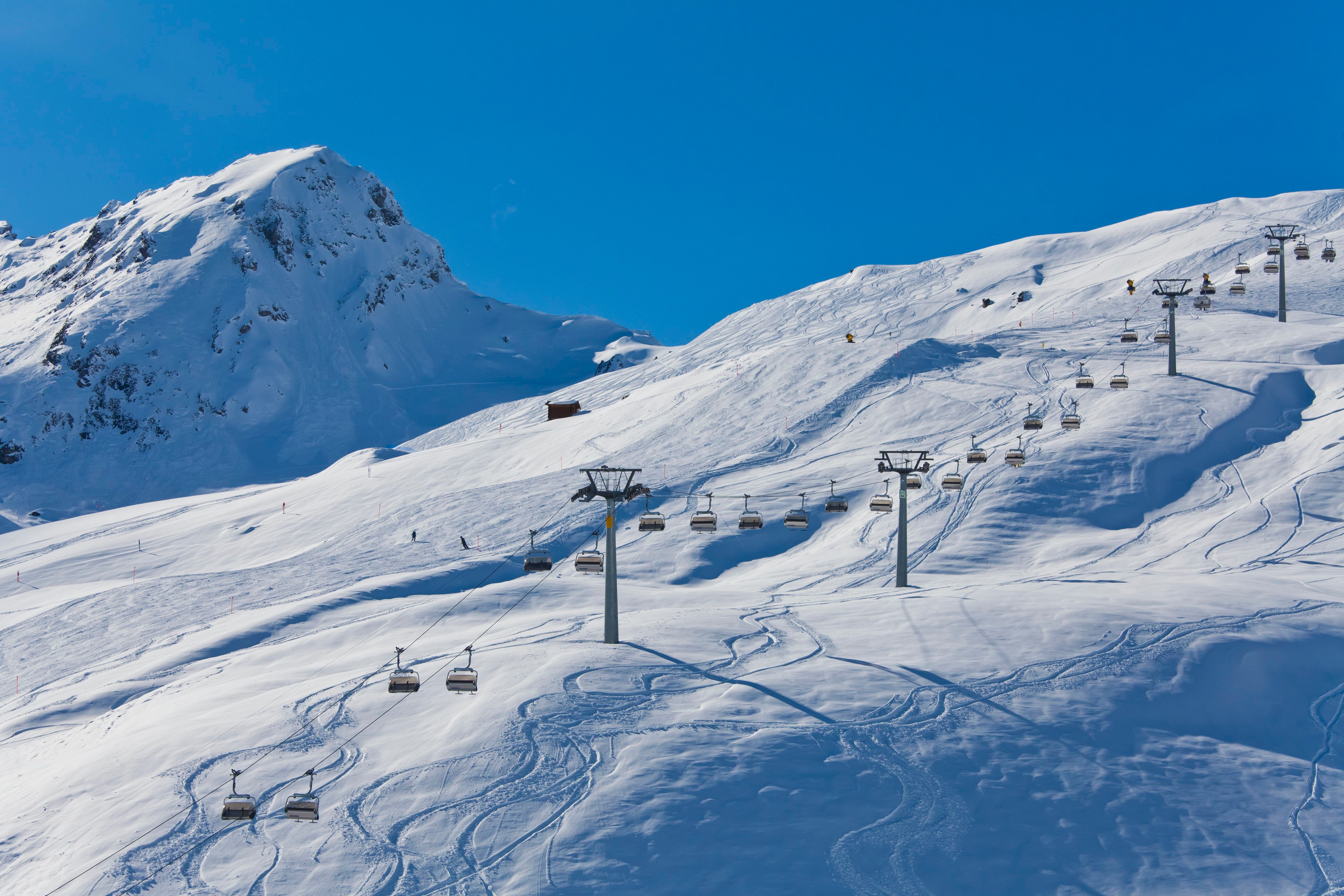 Sessellifte auf einer verschneiten Skipiste in den Bergen bei klarem, blauem Himmel.