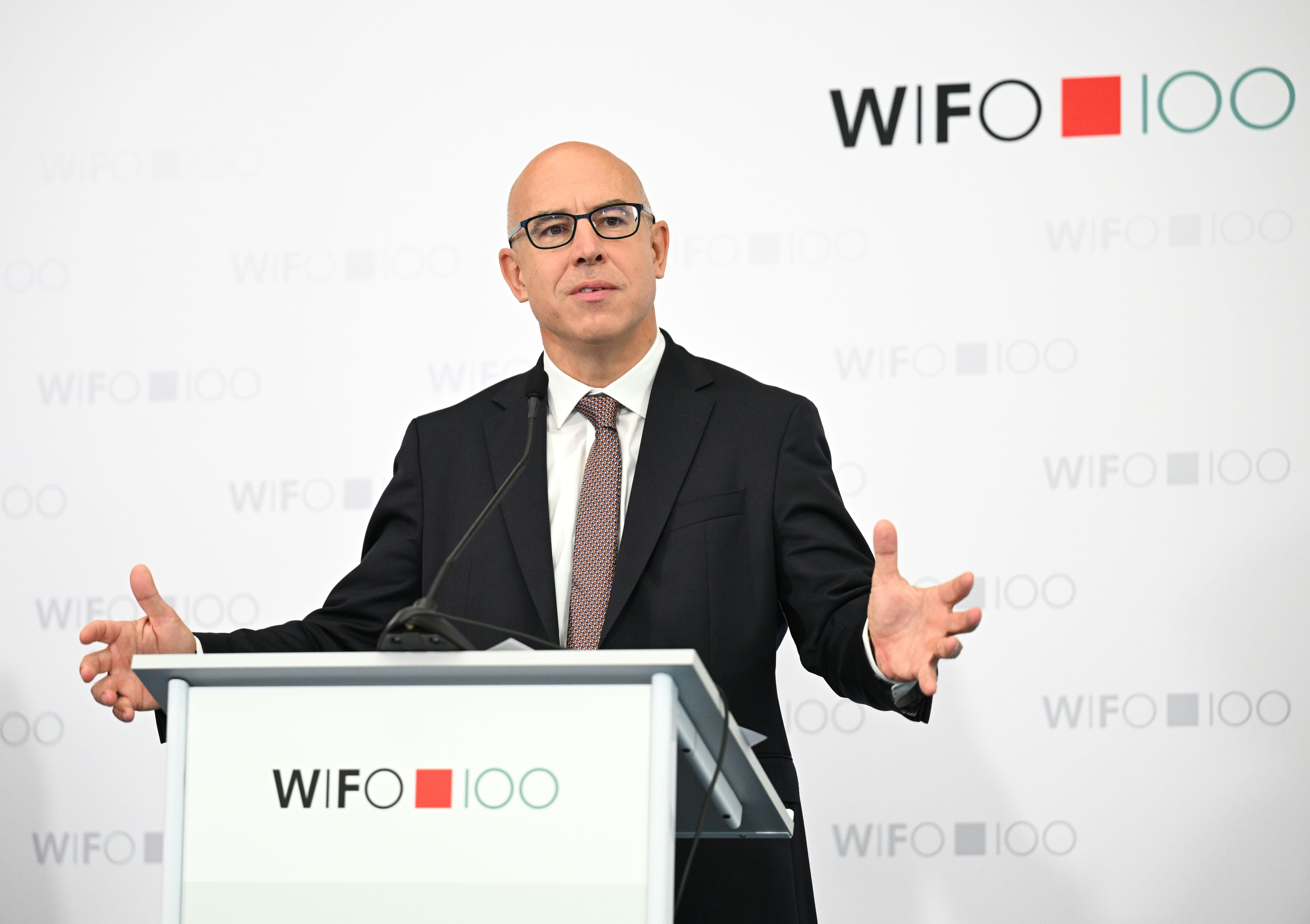 Ein Mann im Anzug spricht bei einer Pressekonferenz am Rednerpult mit WIFO-Logo.