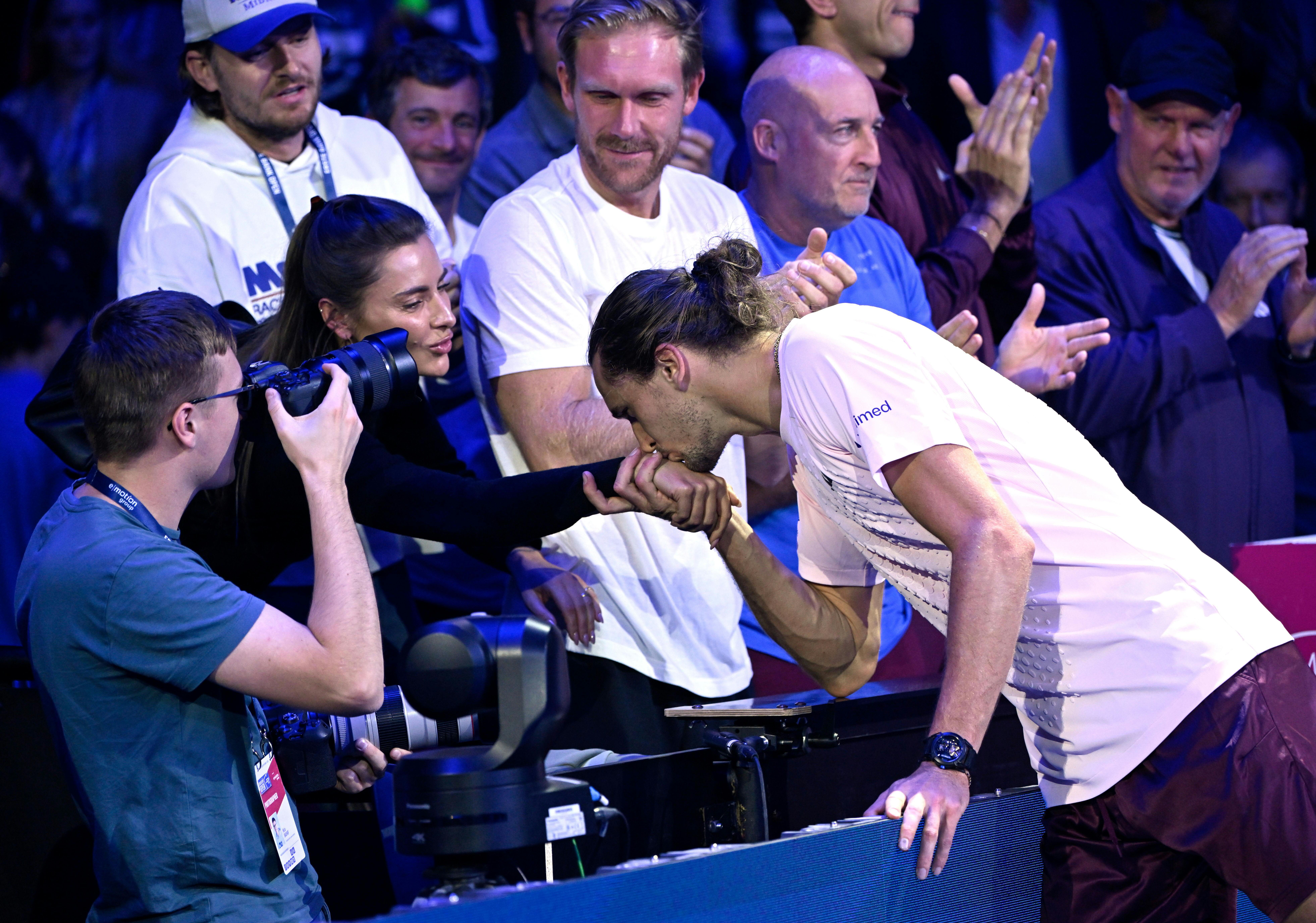 Alexander Zverev küsst Sophia Thomallas Hand beim Tennisturnier in Wien, umgeben von Zuschauern.