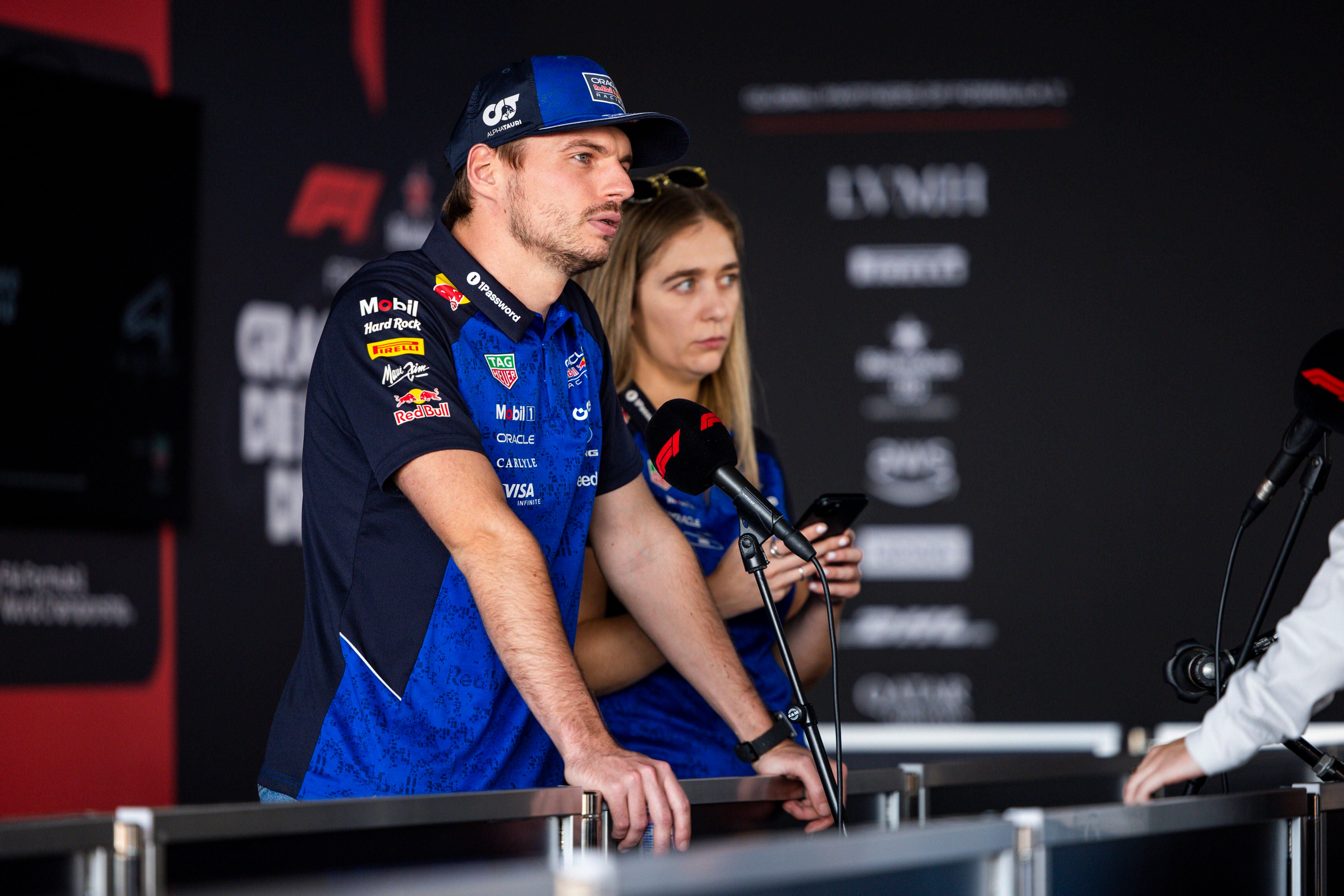 Ein Formel-1-Fahrer gibt bei einer Pressekonferenz ein Interview, daneben steht eine Teamkollegin.